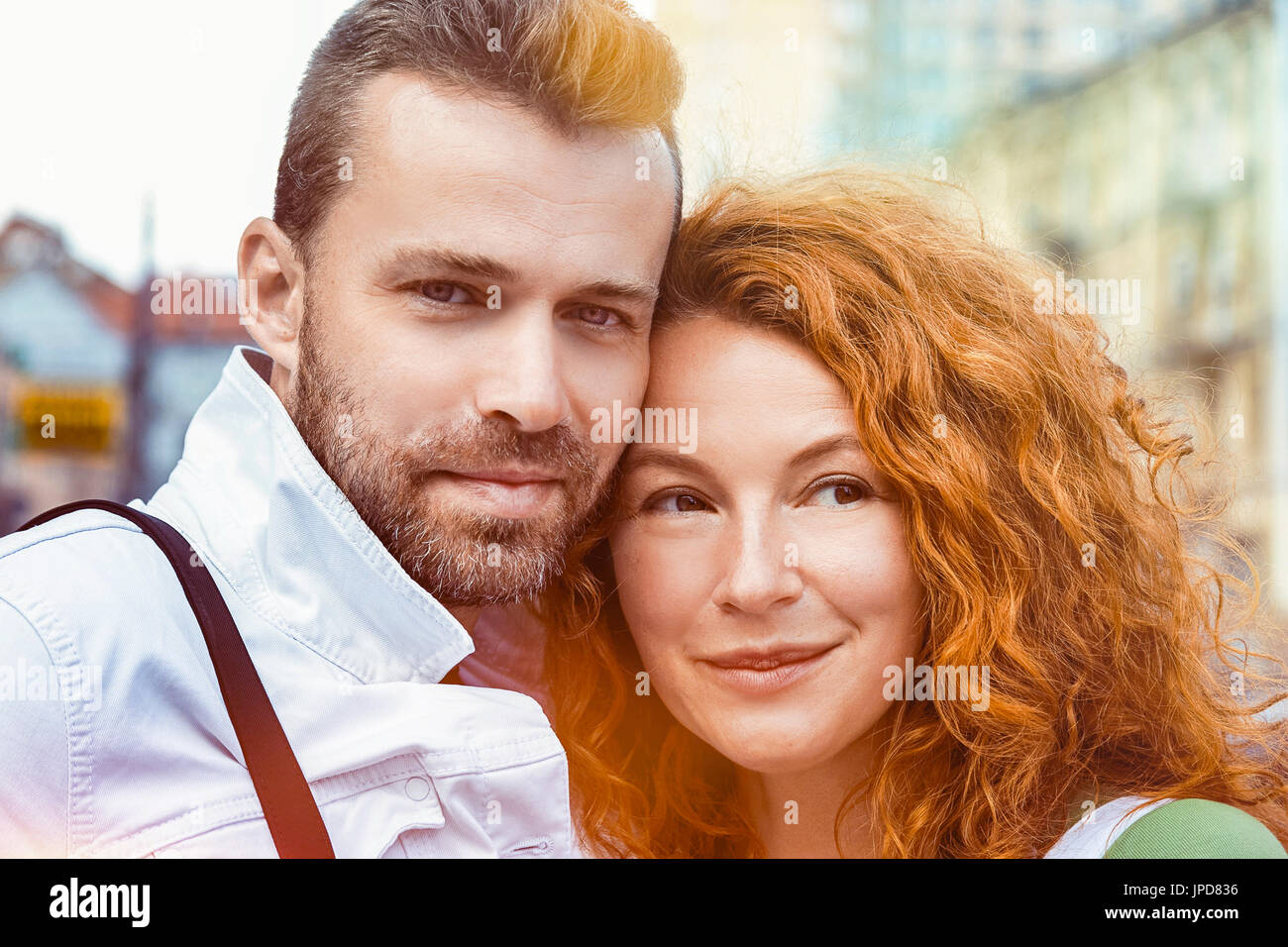 Persone di mezza età sposato l uomo e la donna in posa sulla fotocamera. Dai capelli rossi donna e uomo barbuto, street sunshine sfondo Foto Stock