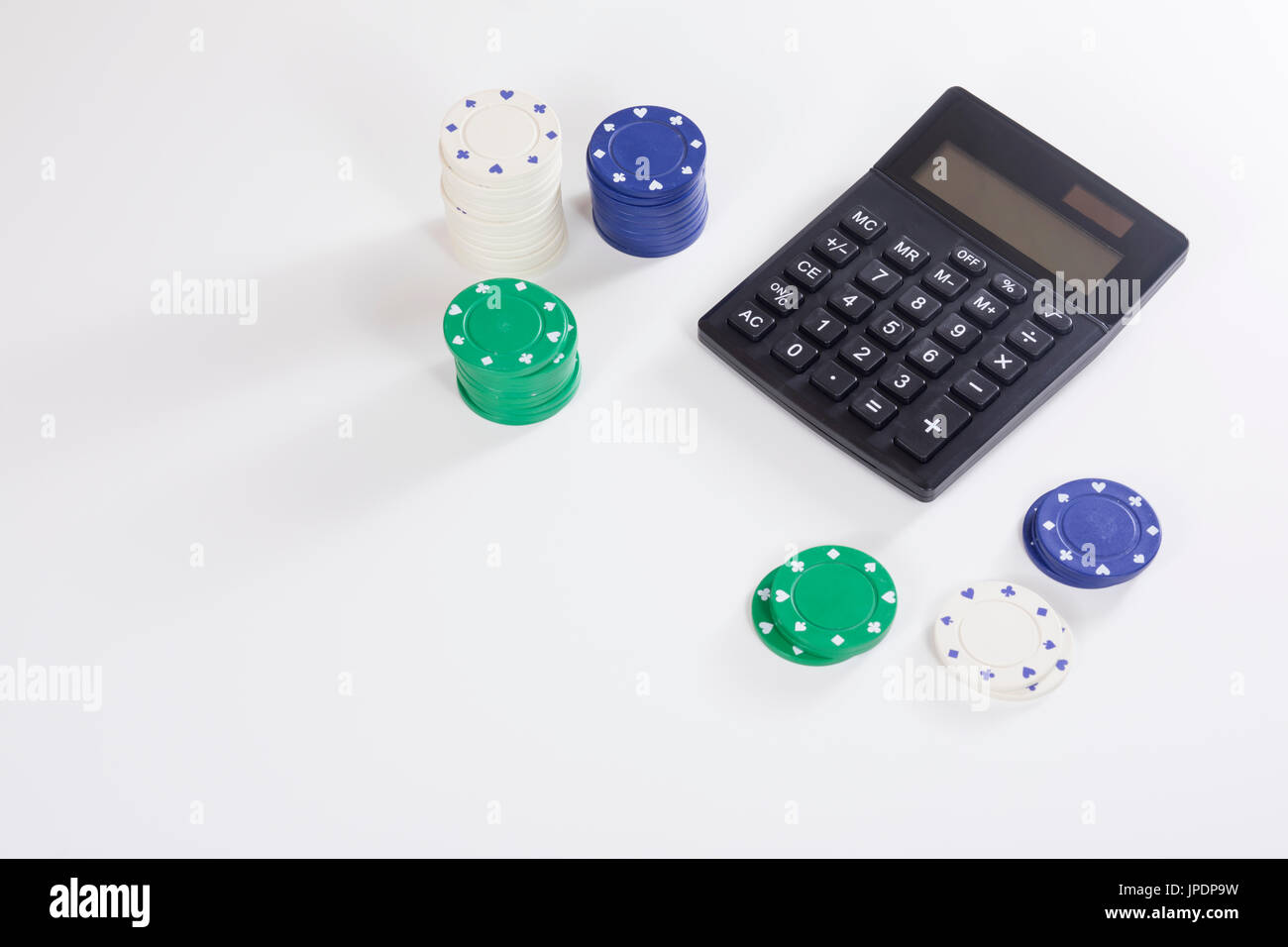 Calcolatrice nera con vari poker chips su sfondo bianco con una leggera ombra e spazio di copia Foto Stock