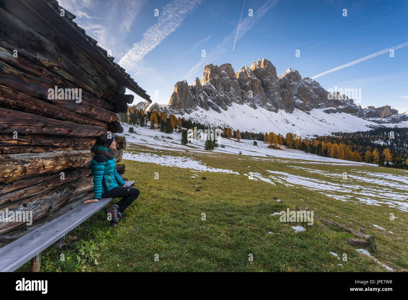 Ragazza seduta su una panchina ammirando la vista del GeislerVal di Funes, Trentino Alto Adige, Italia. Foto Stock