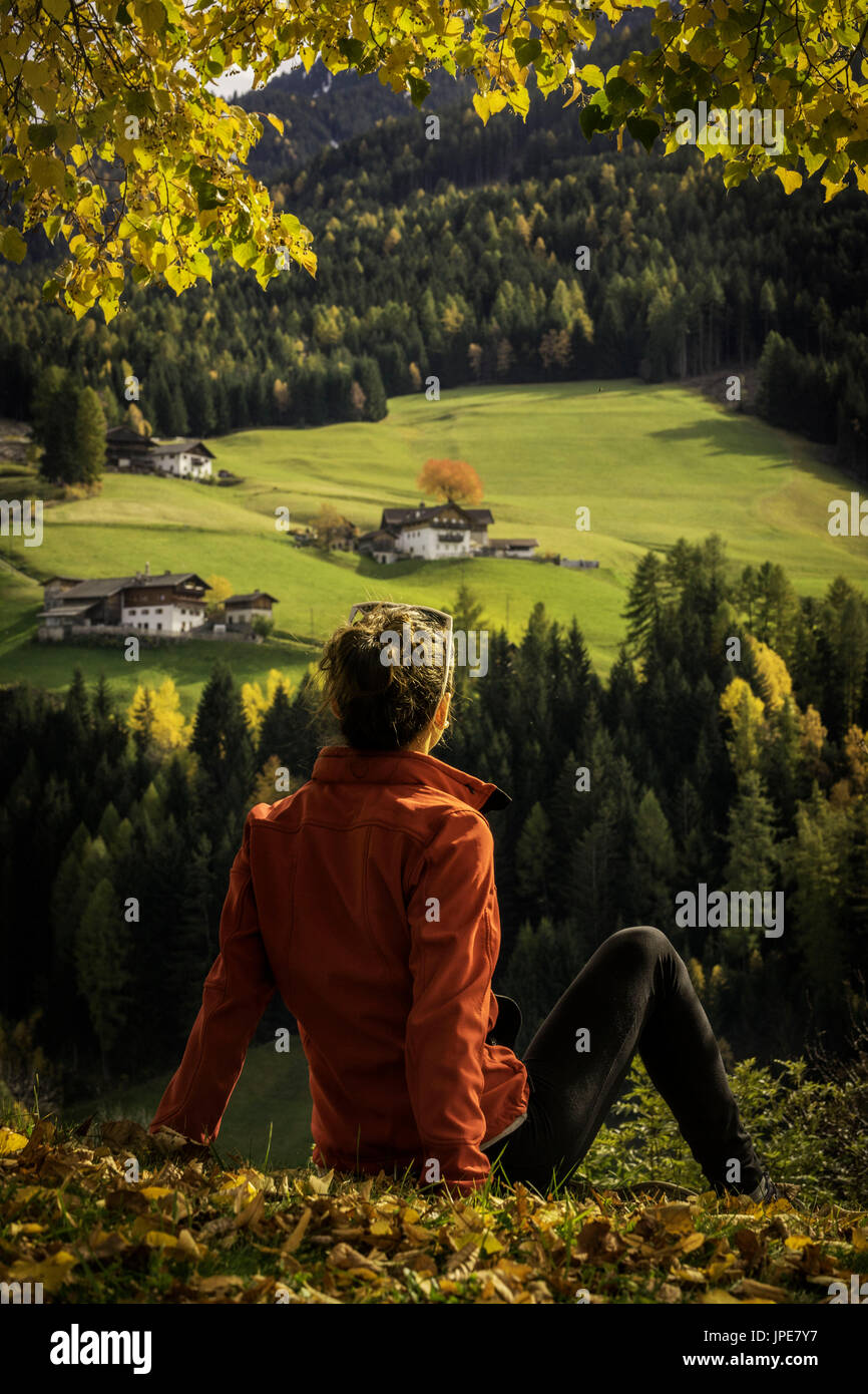 Ragazza seduta sul archiviato ammirando il panorama della Val di Funes, Trentino Alto Adige, Italia. Foto Stock