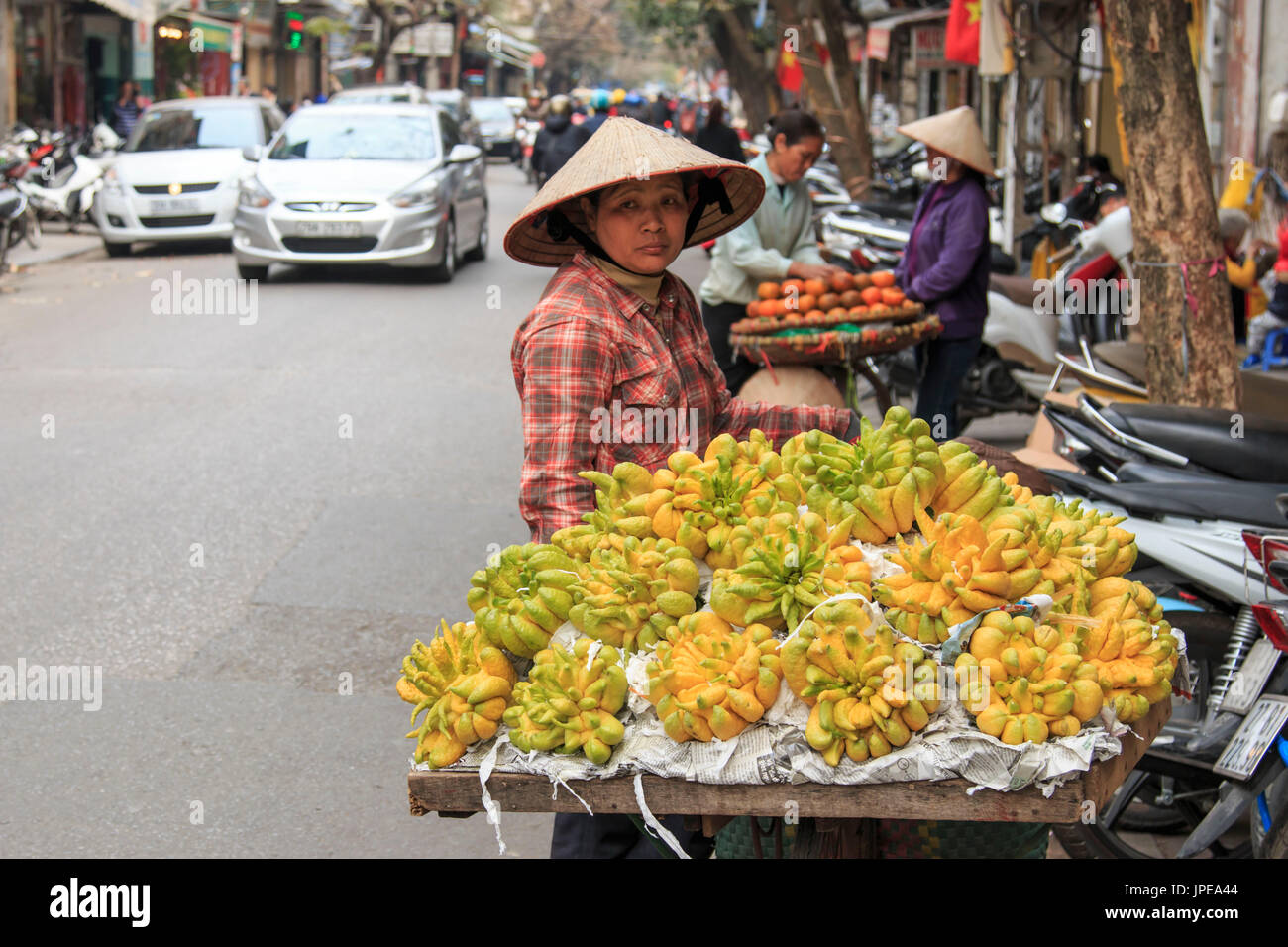 Donna vendita di Buddha la mano di limoni in una strada di Hanoi, Vietnam Foto Stock