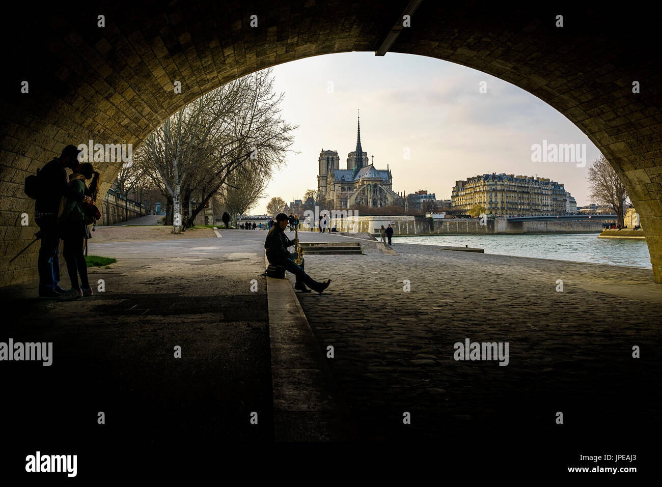 Due Amanti bacio e un musicista sotto un ponte lungo il fiume Senna, vicino a Notre Dame, Paris, Francia. Foto Stock