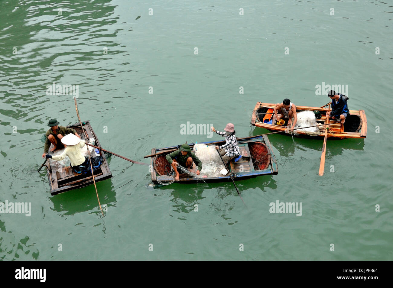 Il Vietnam, Halong Bay. Gli abitanti dei villaggi galleggianti, la pesca con reti sulle caratteristiche imbarcazioni in legno Foto Stock