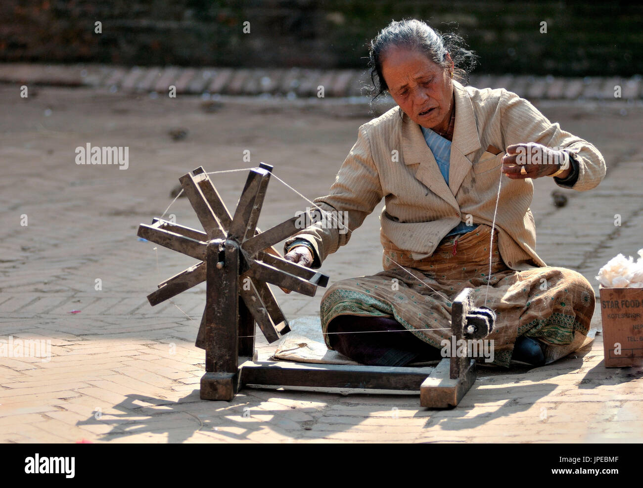 Kathmandu, troverete varie artigiani intenti sul loro lavoro. Questa donna è un tessitore e si dedicò alla sua lana in una piazza di Bhaktapur, Nepal. Foto Stock