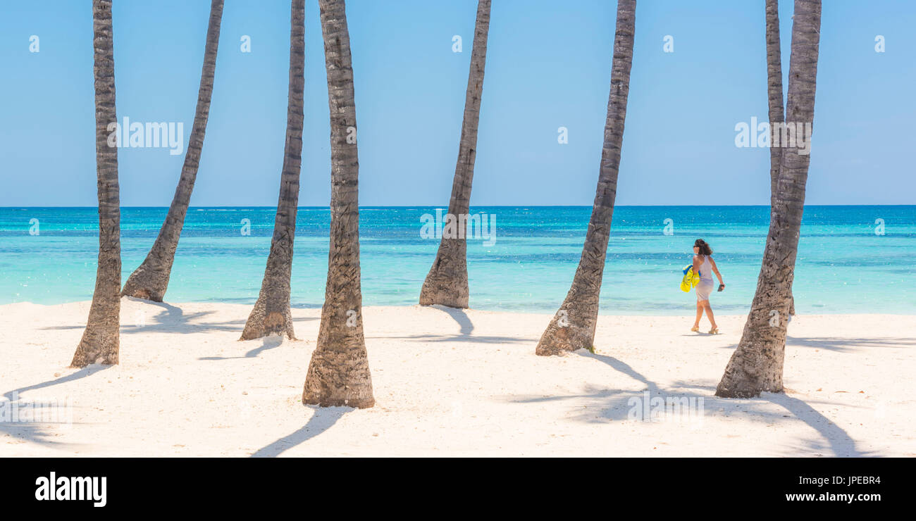 Spiaggia Juanillo (playa Juanillo), Punta Cana, Repubblica Dominicana. Donna di camminare sulla spiaggia orlata di palme (MR). Foto Stock