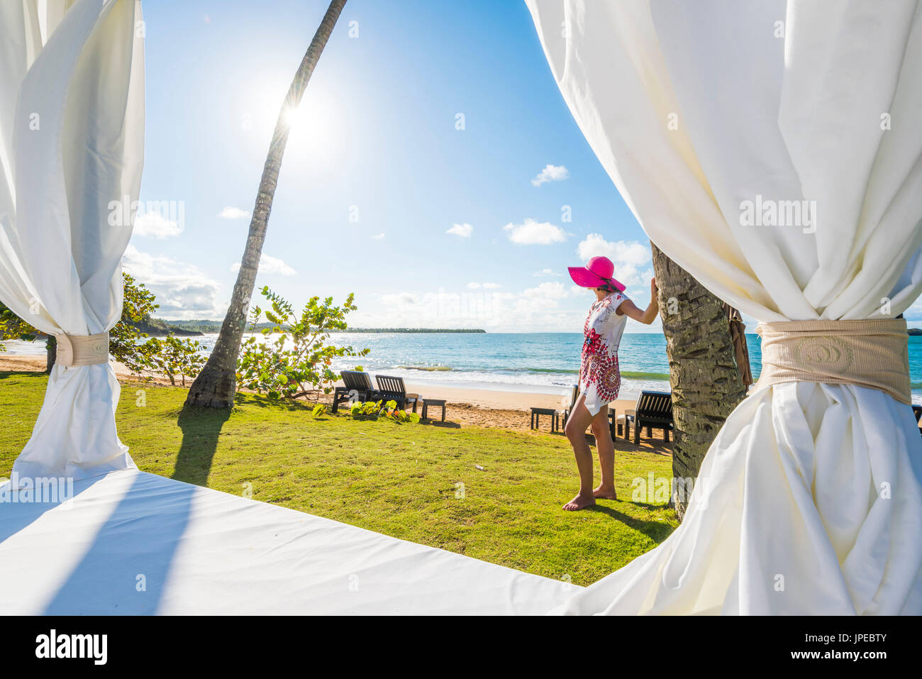 Playa Moron, Las Terrenas, penisola di Samana, Repubblica Dominicana. Bella donna ammirando la vista da da un lettino in spiaggia (MR). Foto Stock