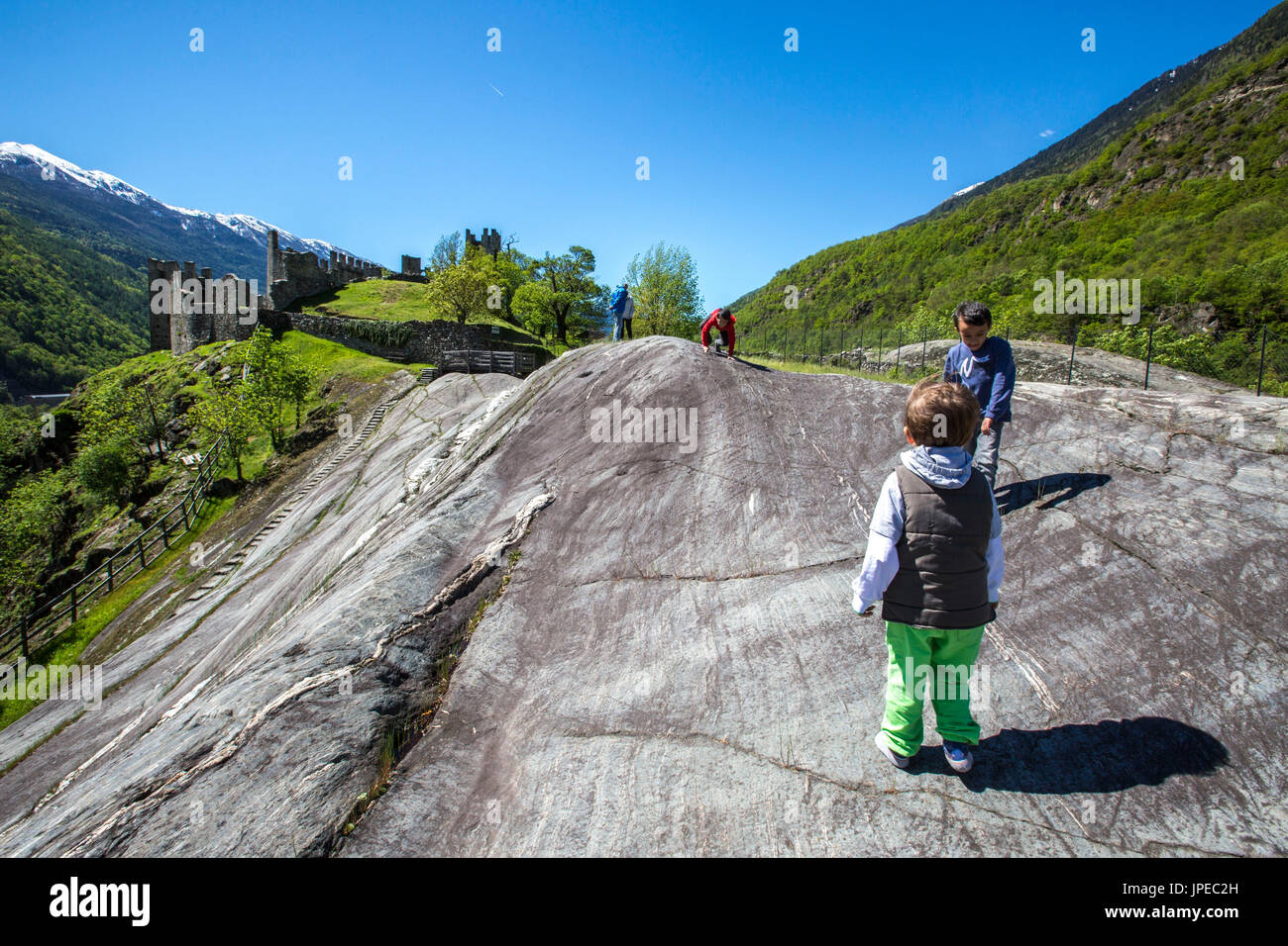 I bambini la ricerca di incisioni rupestri su enorme rupe Magna. Grosio. Provincia di Sondrio. La Valtellina. Lombardia. L'Italia. Europa Foto Stock