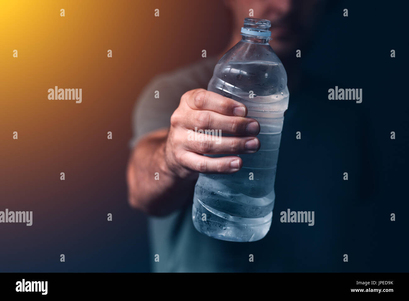 Uomo con una bottiglia di acqua fresca potabile per il ristoro e reidratazione Foto Stock