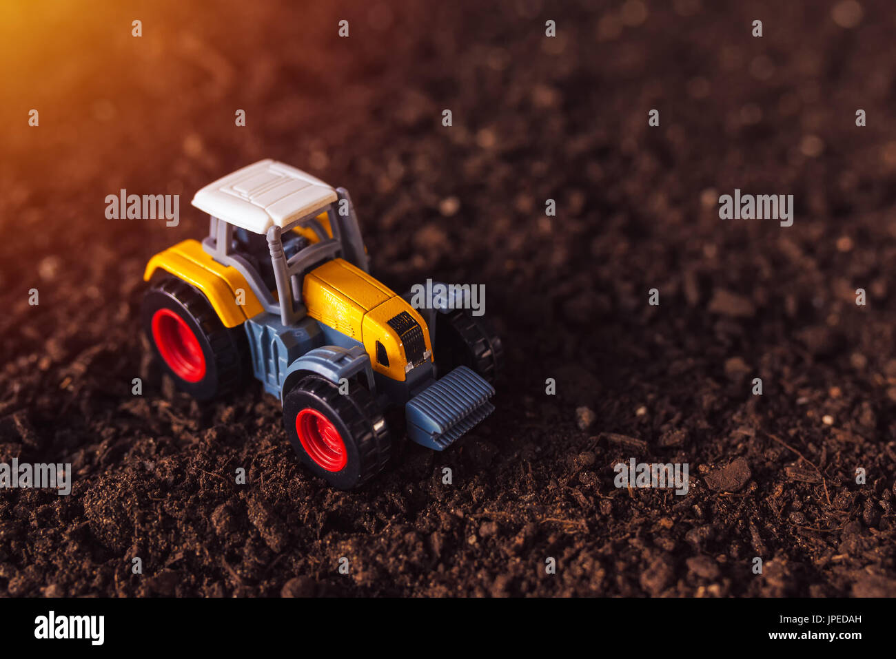 Trattore agricolo giocattolo sul suolo fertile terreno Foto Stock