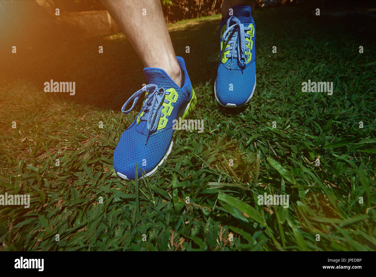 Fare jogging sul prato verde sullo sfondo di close-up. Colorate blu scarpe run Foto Stock