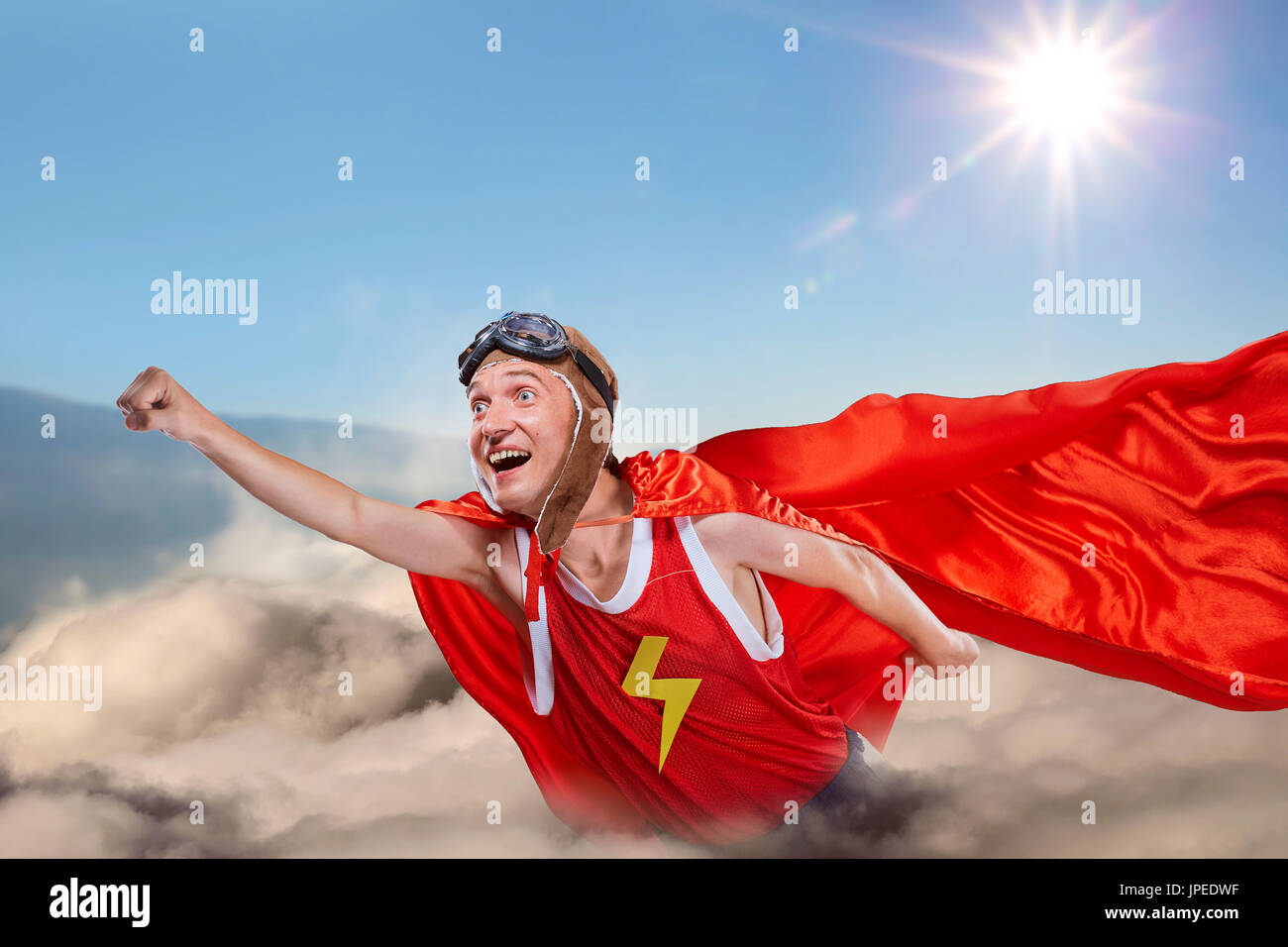 Un divertente super hero volare sopra le nuvole nel cielo Foto Stock