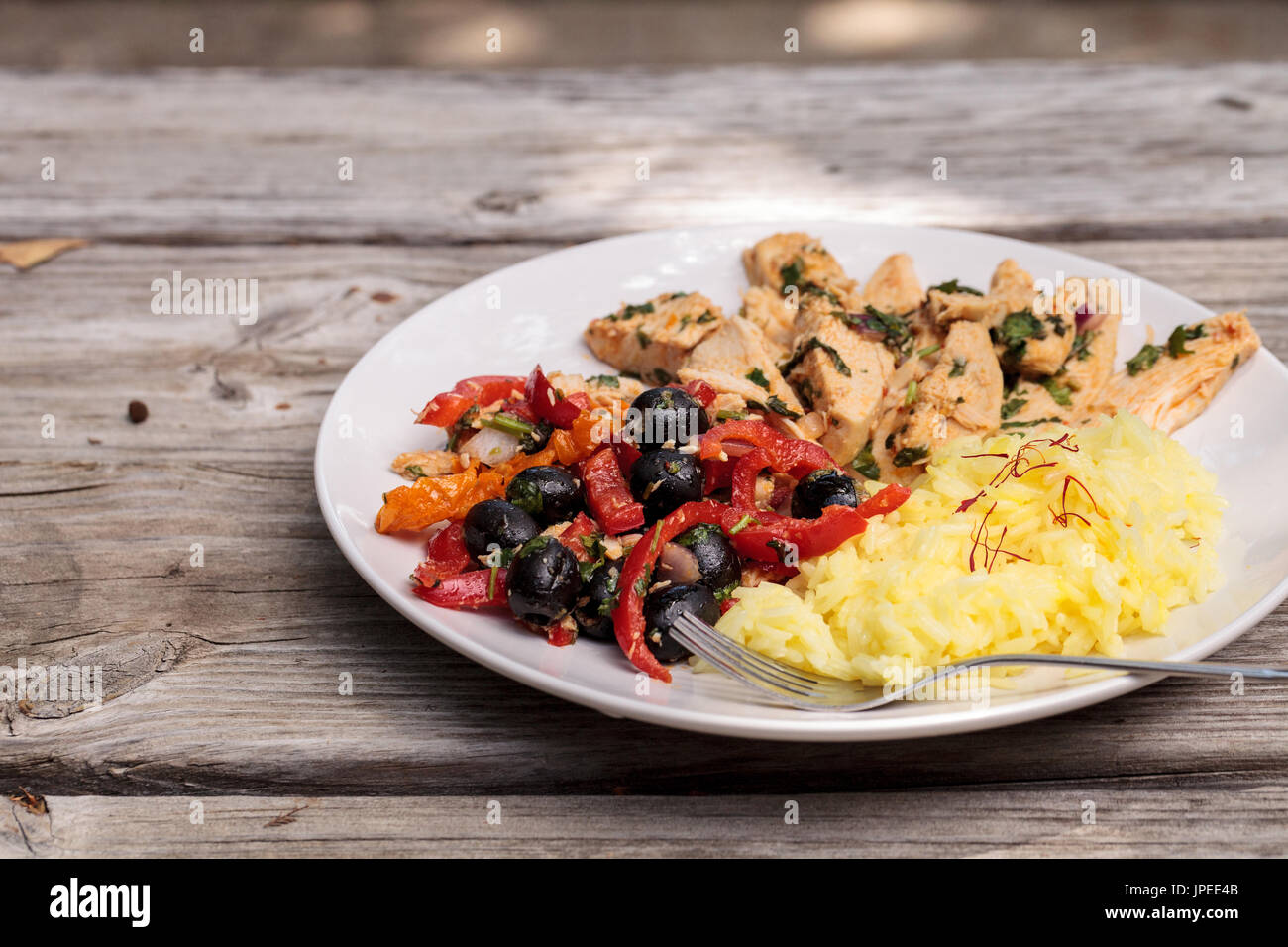 Pollo speziato Diablo con il coriandolo, olive e peperoni, aglio e cipolla servita su giallo zafferano riso. Foto Stock