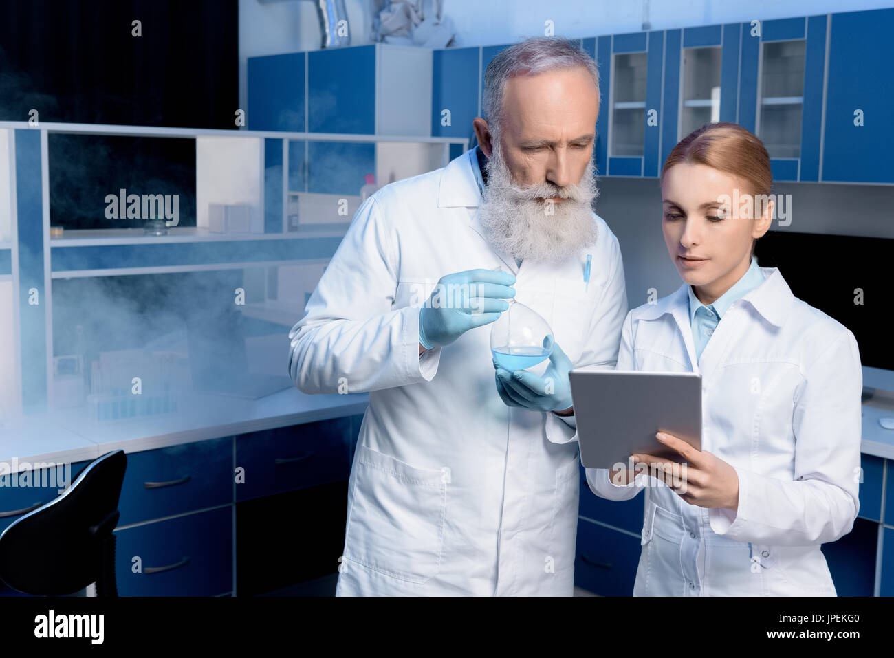 Considerato gli scienziati in camice da laboratorio guardando digitale compressa in laboratorio Foto Stock