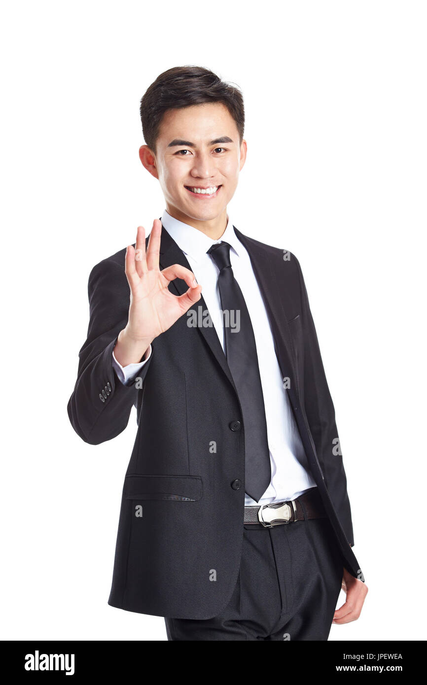 Giovani asian business executive in abbigliamento formale che mostra un segno OK, felice e sorridente, isolato su sfondo bianco. Foto Stock
