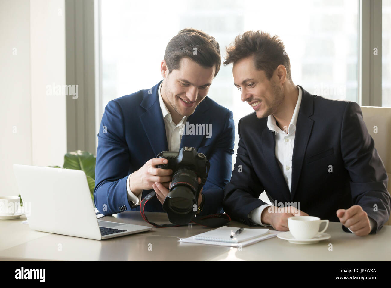Imprenditore entusiasta tenendo la fotocamera professionale, che mostra foto Foto Stock