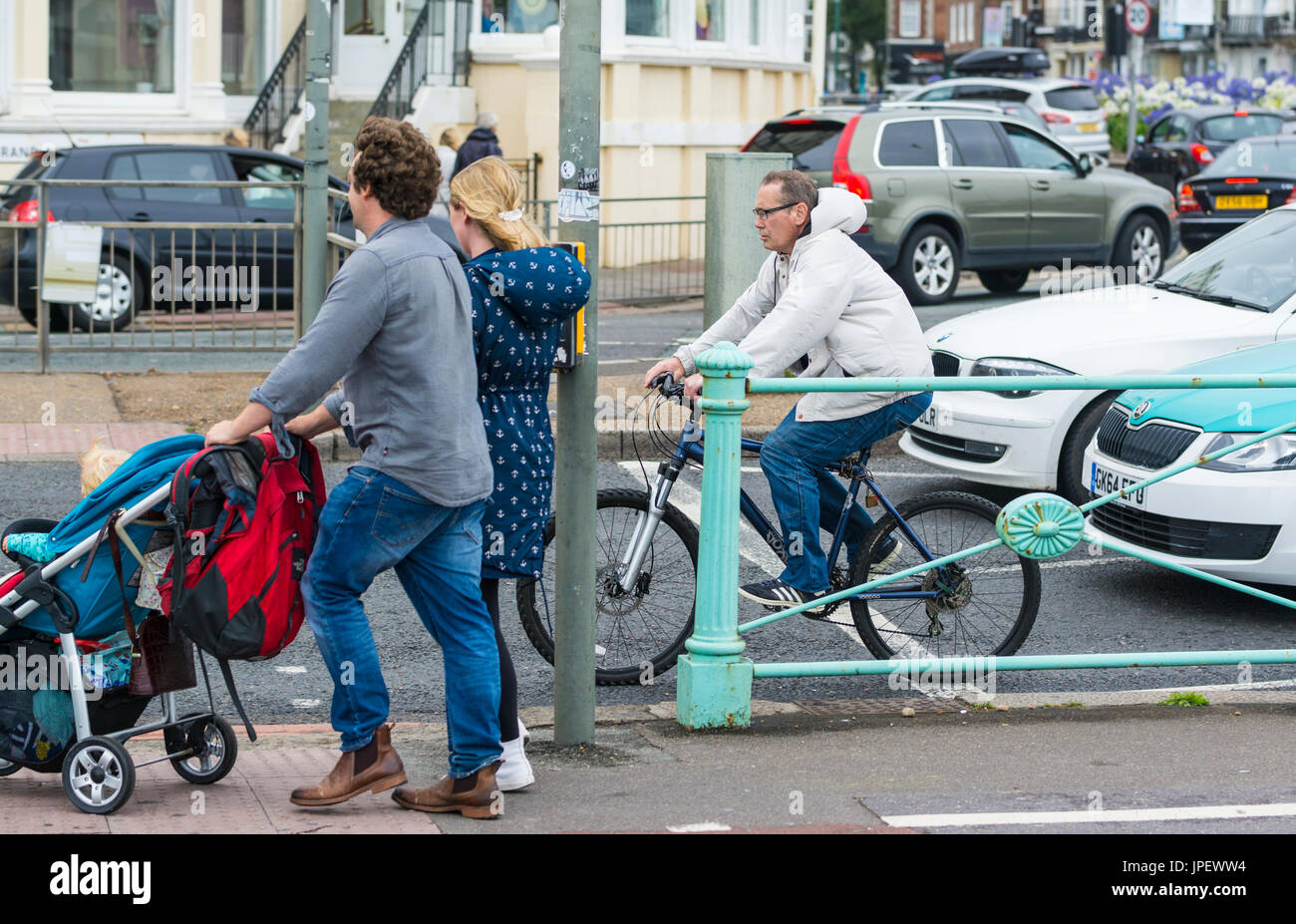 Ciclista maschio violando la legge da cavalcare la sua bicicletta su un semaforo rosso a un pellicano attraversando, quasi di colpire i pedoni. Foto Stock