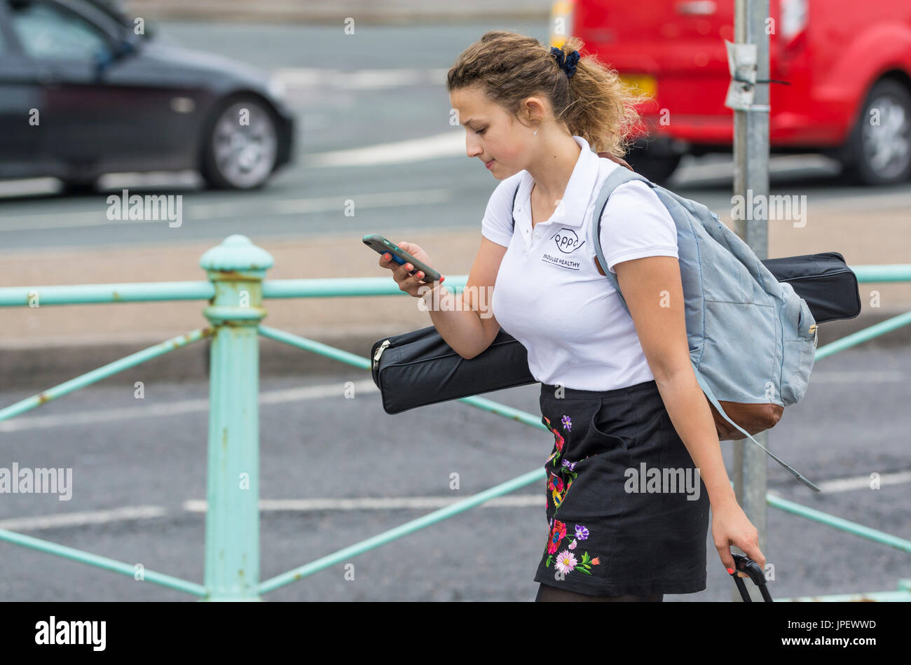 Giovane donna a piedi lungo guardando al telefono cellulare. Cultura online. La vita moderna concezione. Sempre connesso. Foto Stock