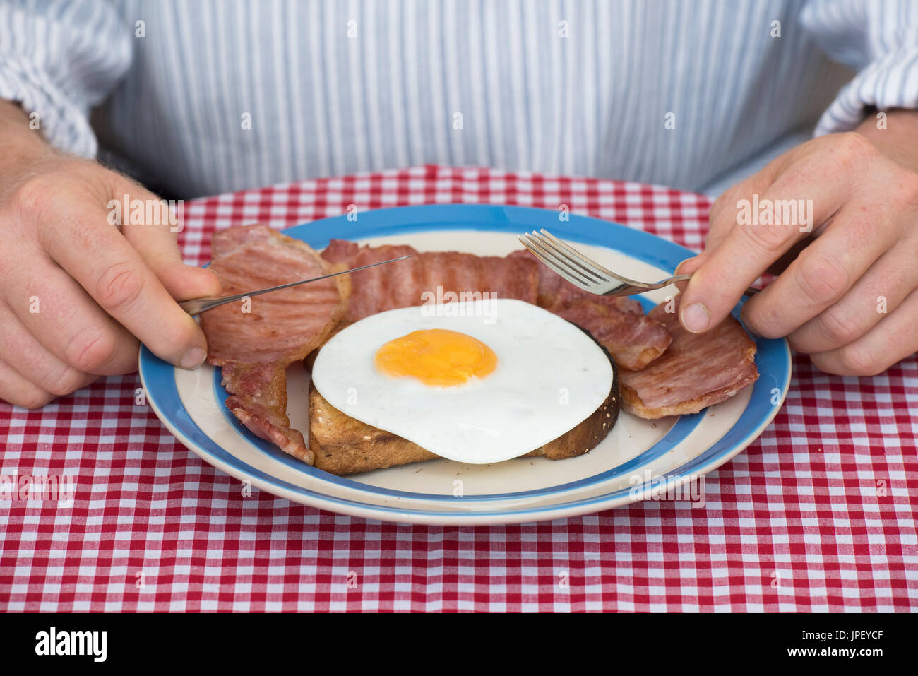 Uomo di mangiare uova fritte e pancetta sul pane tostato. Regno Unito Foto Stock