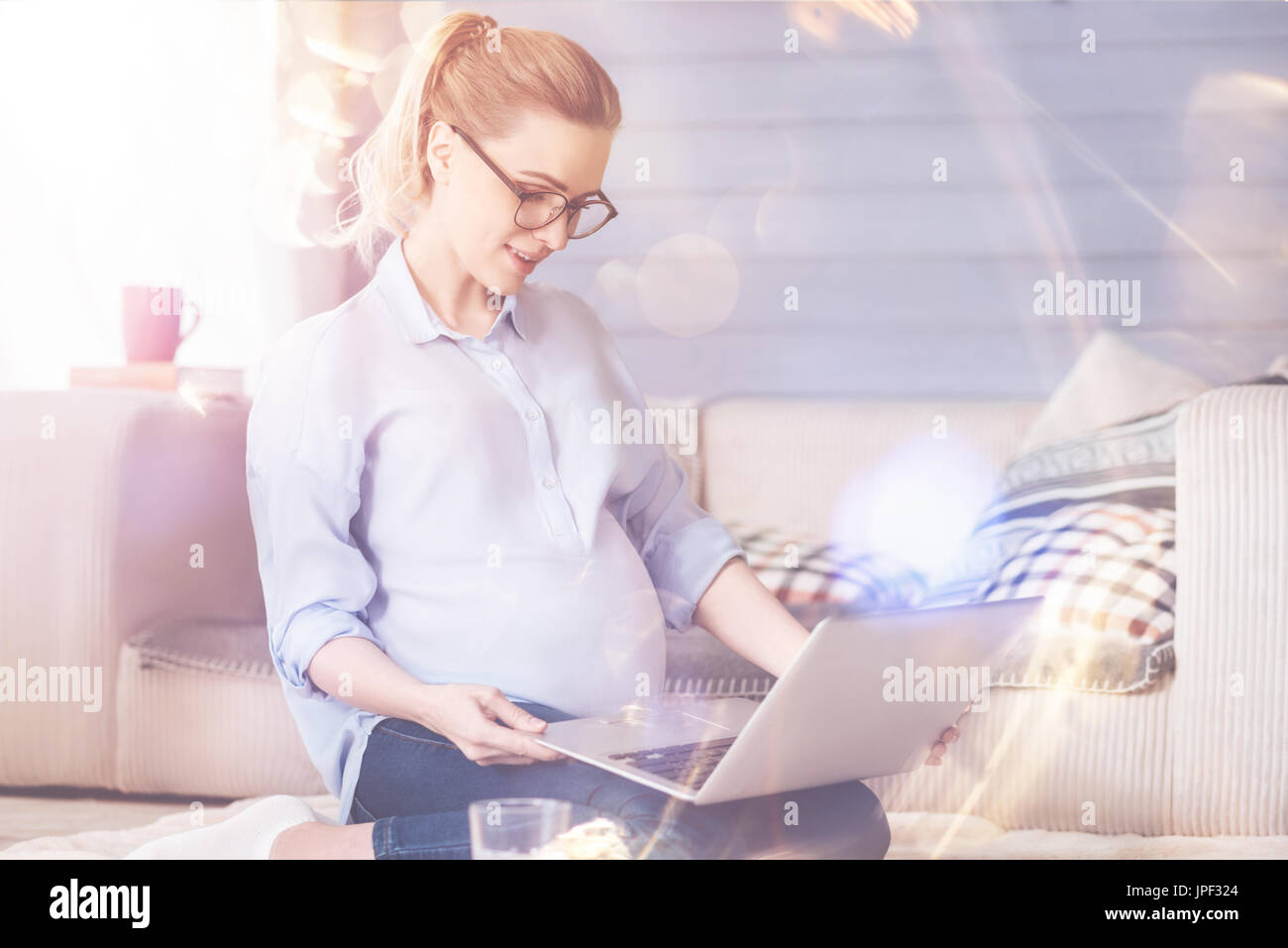 Piacevole donna incinta utilizzando laptop Foto Stock