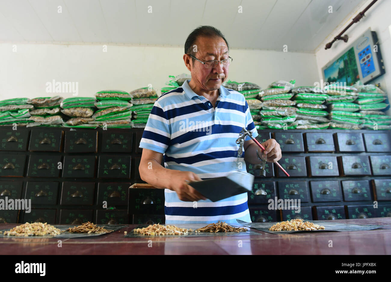 (170802) -- JILIN, 2 agosto 2017 (Xinhua) -- Yue Ruhua seleziona medicina per pazienti a Dakouqin villaggio di Houtuanshan città nella città di Jilin, a nord-est della Cina di provincia di Jilin, 31 luglio 2017. 64-anno-vecchio Yue Ruhua è stato un medico rurale per 37 anni. Diverso da medici in area urbana e rurale i medici devono rendere casa chiamate frequentemente. Secondo Yue Ruhua la moglie di Jing Yuhong, cadde sulla strada robusto e siamo stati alzati fino a tardi per il soccorso di pazienti innumerevoli volte. In 2013, Yue Ruhua è stato diagnosticato con infarto miocardico acuto e inviati alla unità di cure intensive. Gli abitanti di un villaggio sollevato più di 20.000 yuan t Foto Stock