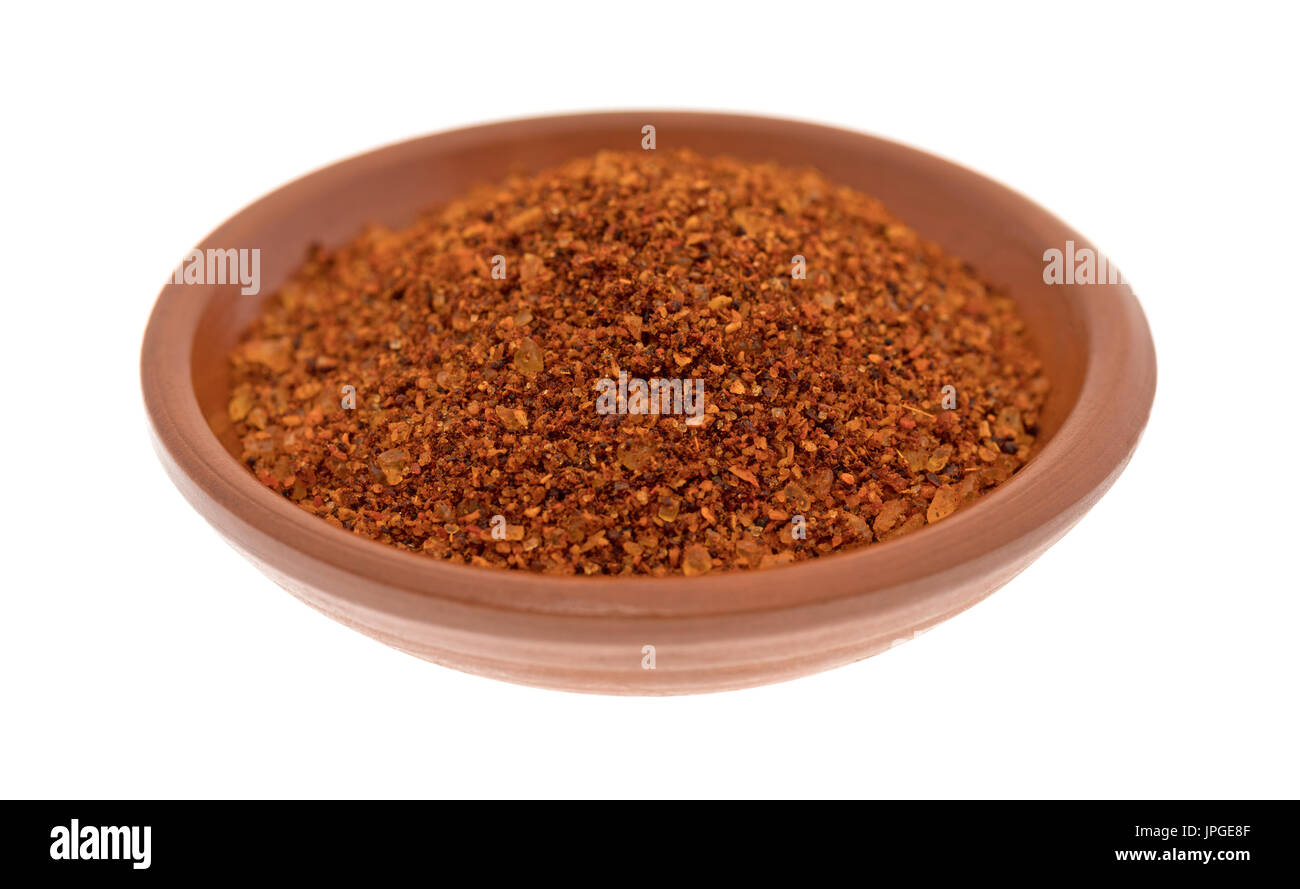 Una piccola rossa argilla ciotola riempita con peperoncino habanero condimento isolato su uno sfondo bianco. Foto Stock