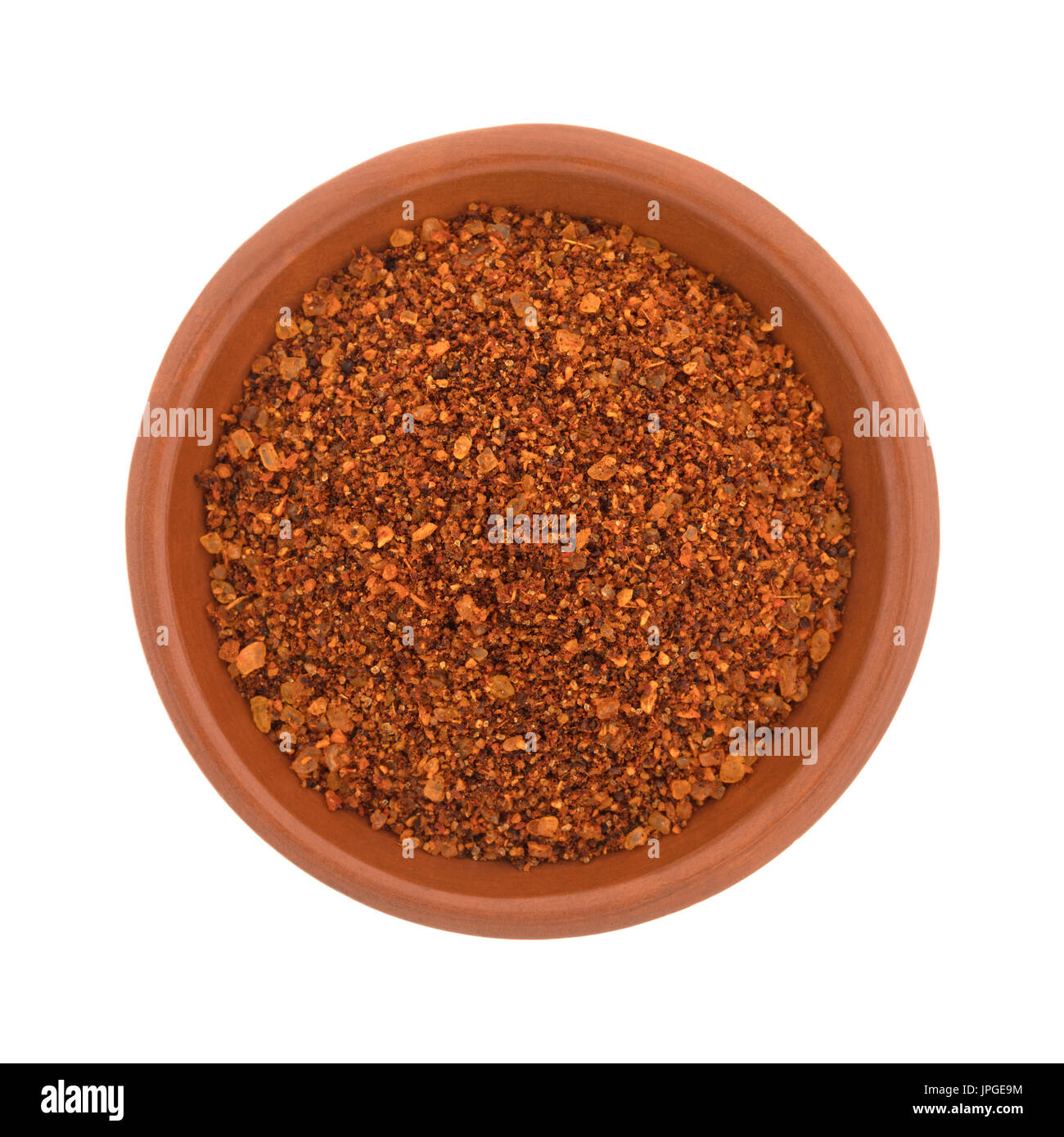 Vista dall'alto di un piccolo argilla rossa ciotola riempita con peperoncino habanero condimento isolato su uno sfondo bianco. Foto Stock