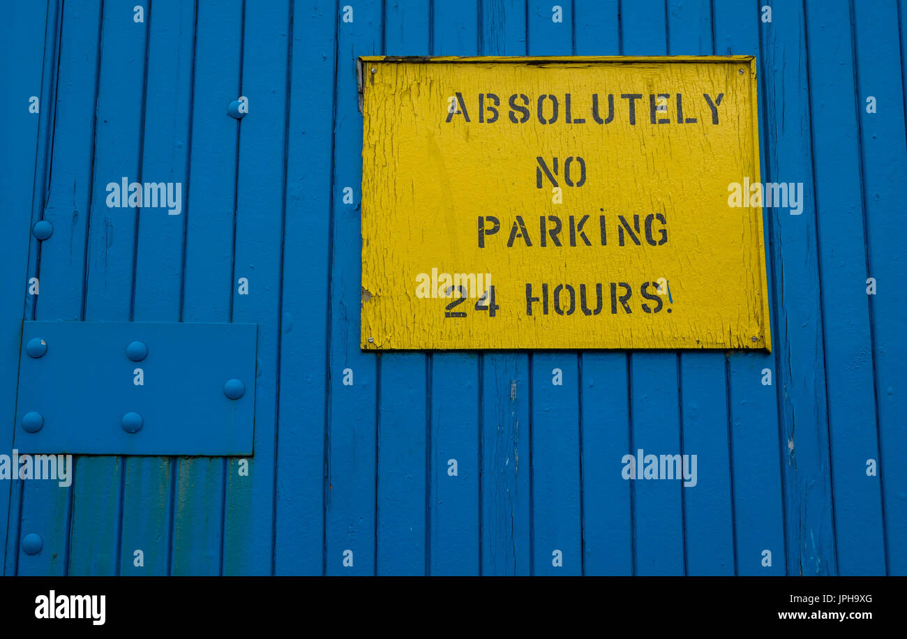 Assolutamente no parcheggio 24 ore cartello giallo su blu porta industriale, la Riva, Leith, Edimburgo, Scozia, Regno Unito Foto Stock