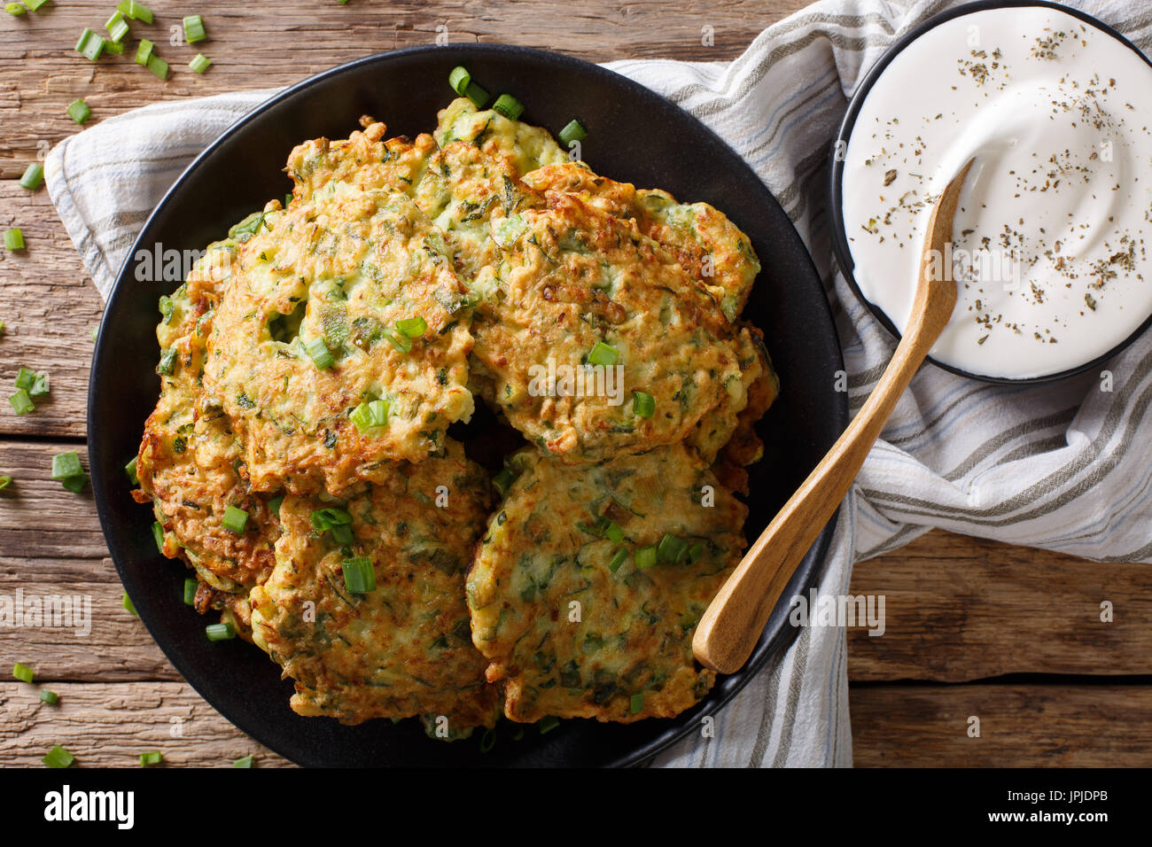 Appena cotte le zucchine frittelle con panna acida vicino sul tavolo. Vista orizzontale dal di sopra Foto Stock