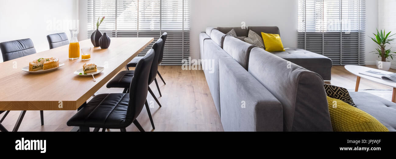 Home interno con tavolo comunale, sedie di colore nero e grigio divano, panorama Foto Stock