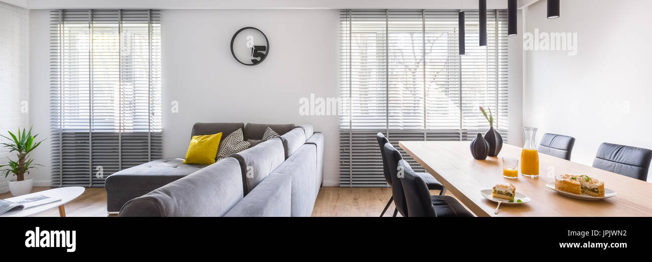 Casa moderna con interni tavolo comunale, sedie di colore nero e grigio divano, panorama Foto Stock