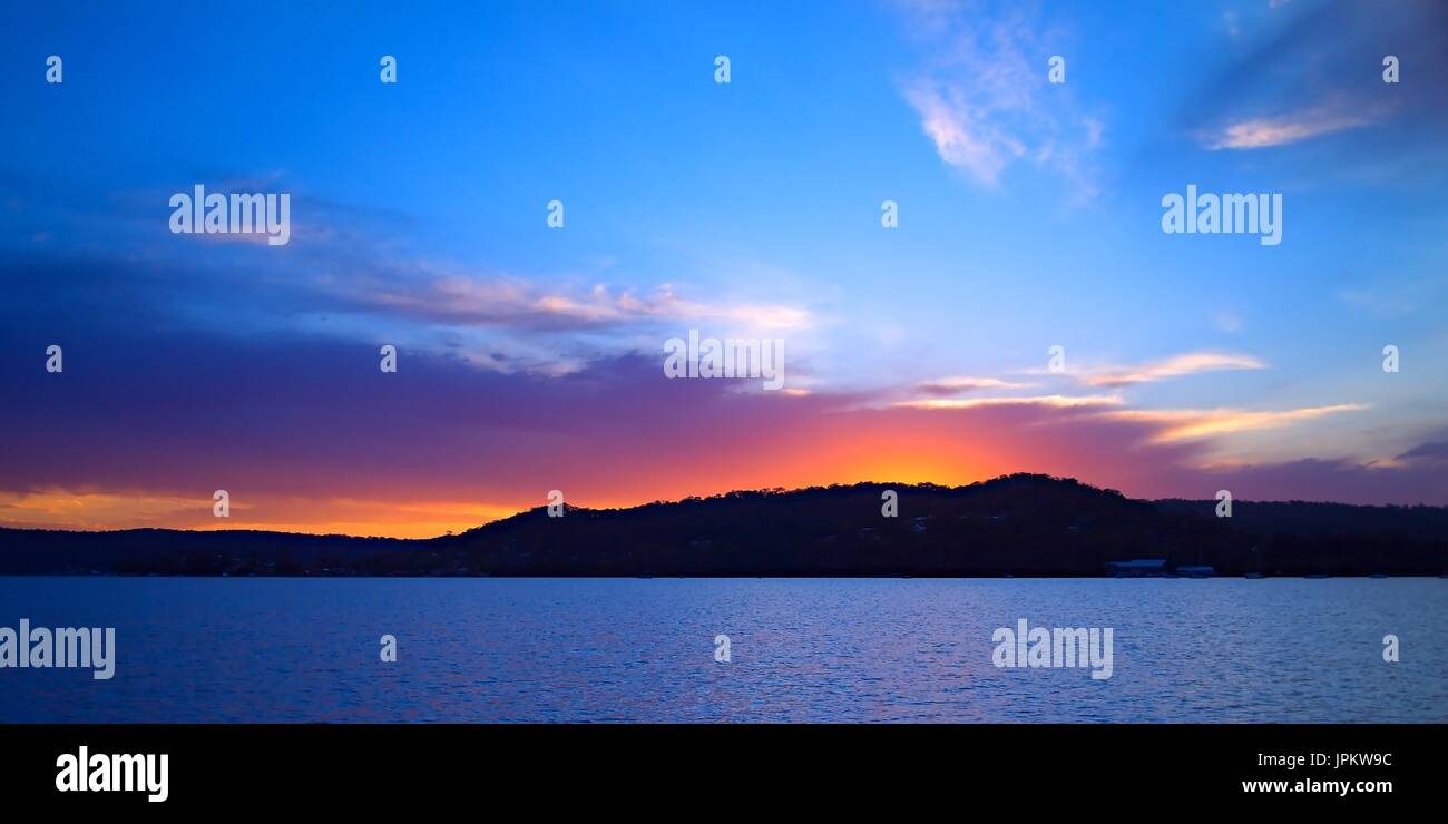 Vivid color cremisi e blu seascape paesaggi acquatici tramonto, oltre Saratoga, con riflessi dell'acqua. Catturate su acqua di Brisbane, Gosford, Central Coast, Nuovo modo Foto Stock