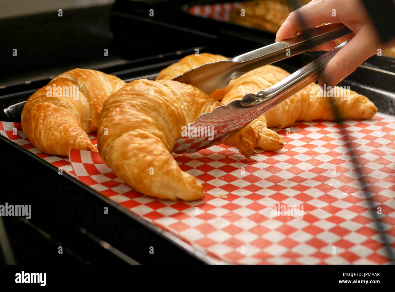 Donna comprare croissant pane all'interno di comprare alimenti bassa store Foto Stock