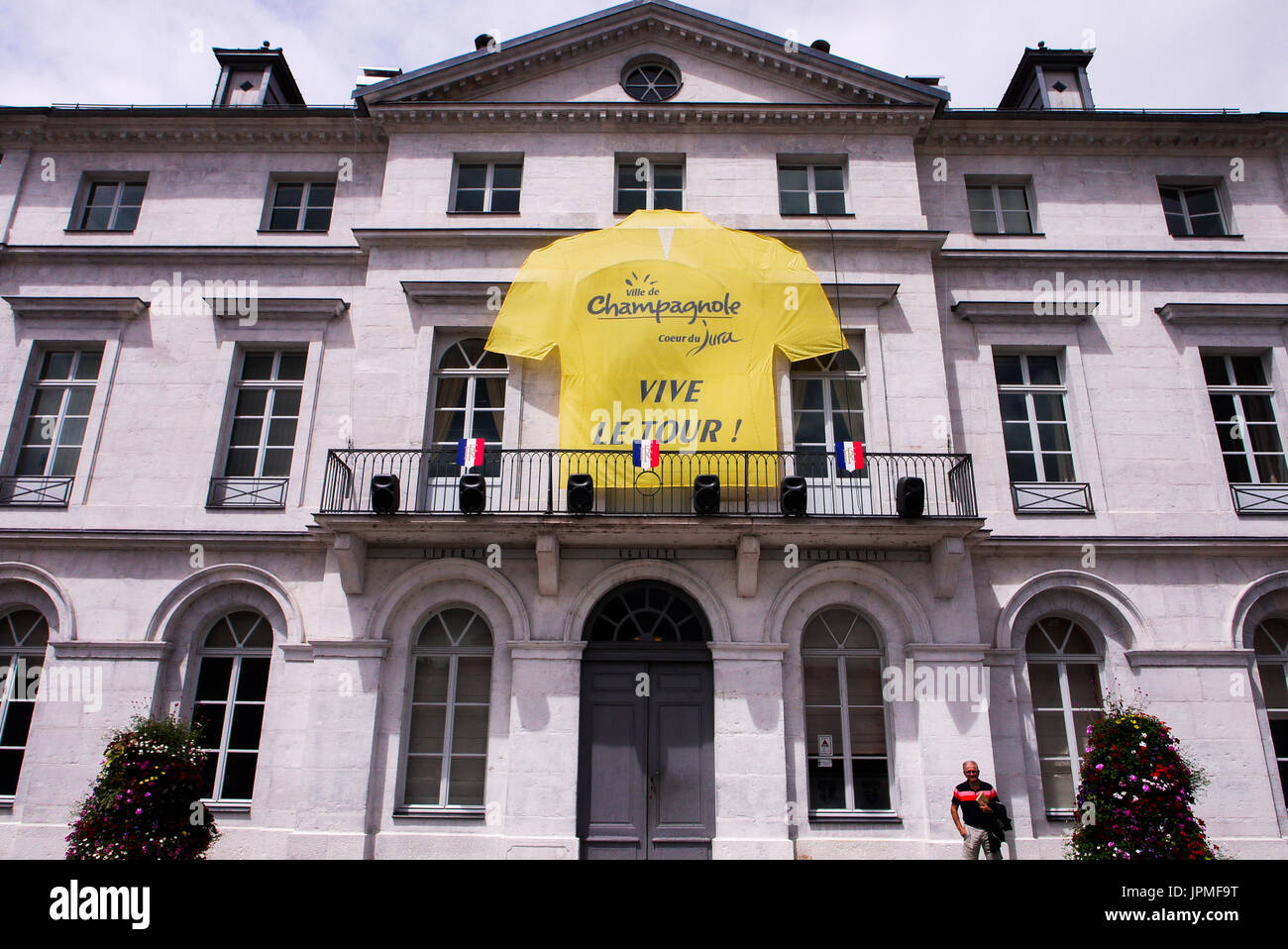 Un giallo giubbotto in bicicletta si blocca sulla facciata della townhal di Champagnole, Giura, Francia Foto Stock