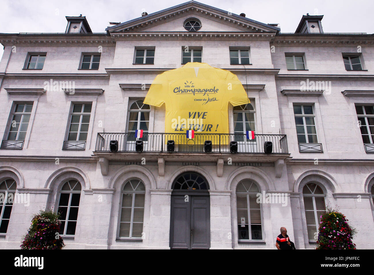 Un giallo giubbotto in bicicletta si blocca sulla facciata della townhal di Champagnole, Giura, Francia Foto Stock