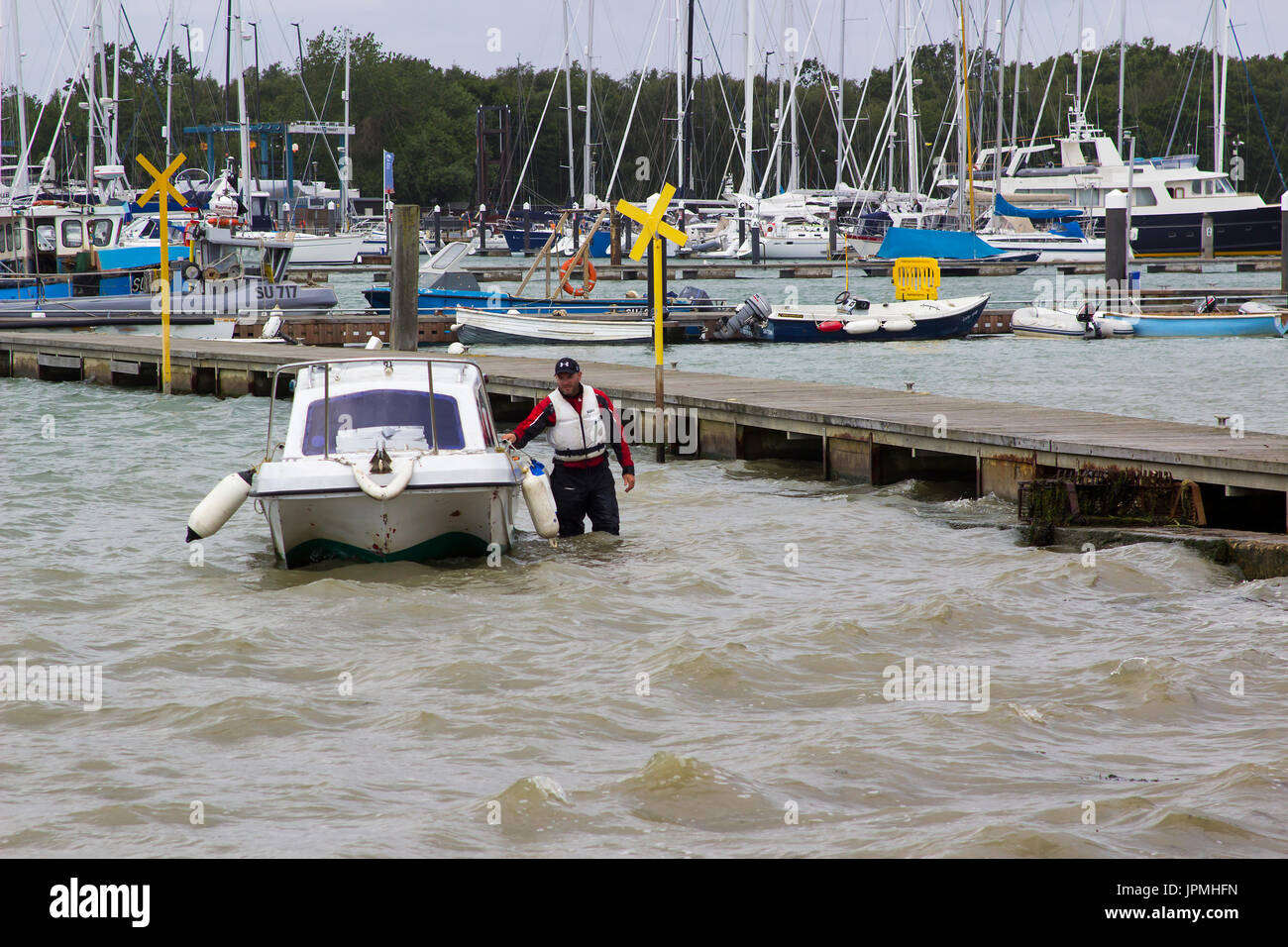 Un proprietario di imbarcazione portando la sua piccola fibra di vetro barca verso la riva in Warsash, Hampshire ad un rimorchio di attesa al fine di estrarre dall'acqua per Foto Stock