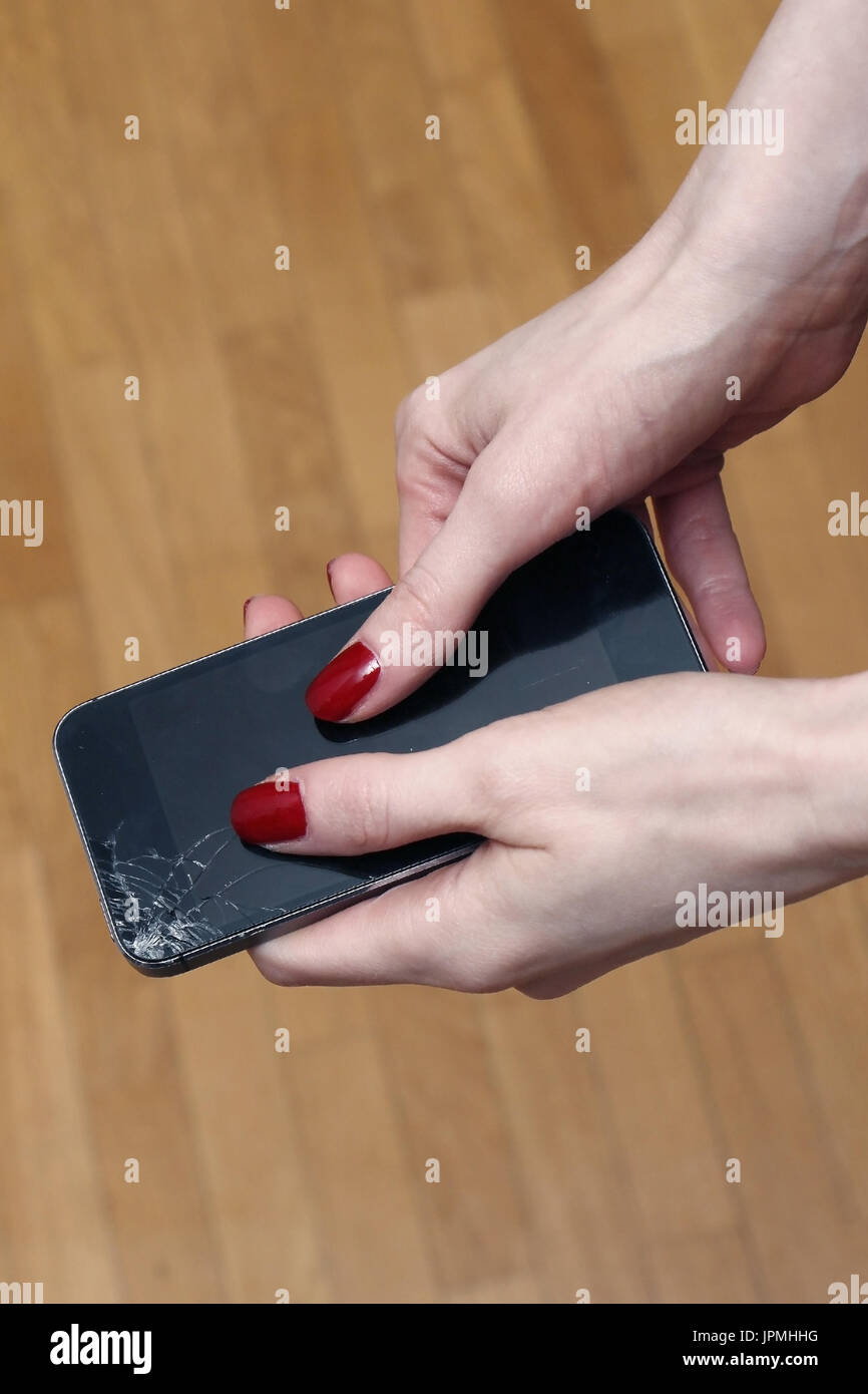 Mani femminili holding rotto smartphone con schermo incrinato Foto Stock