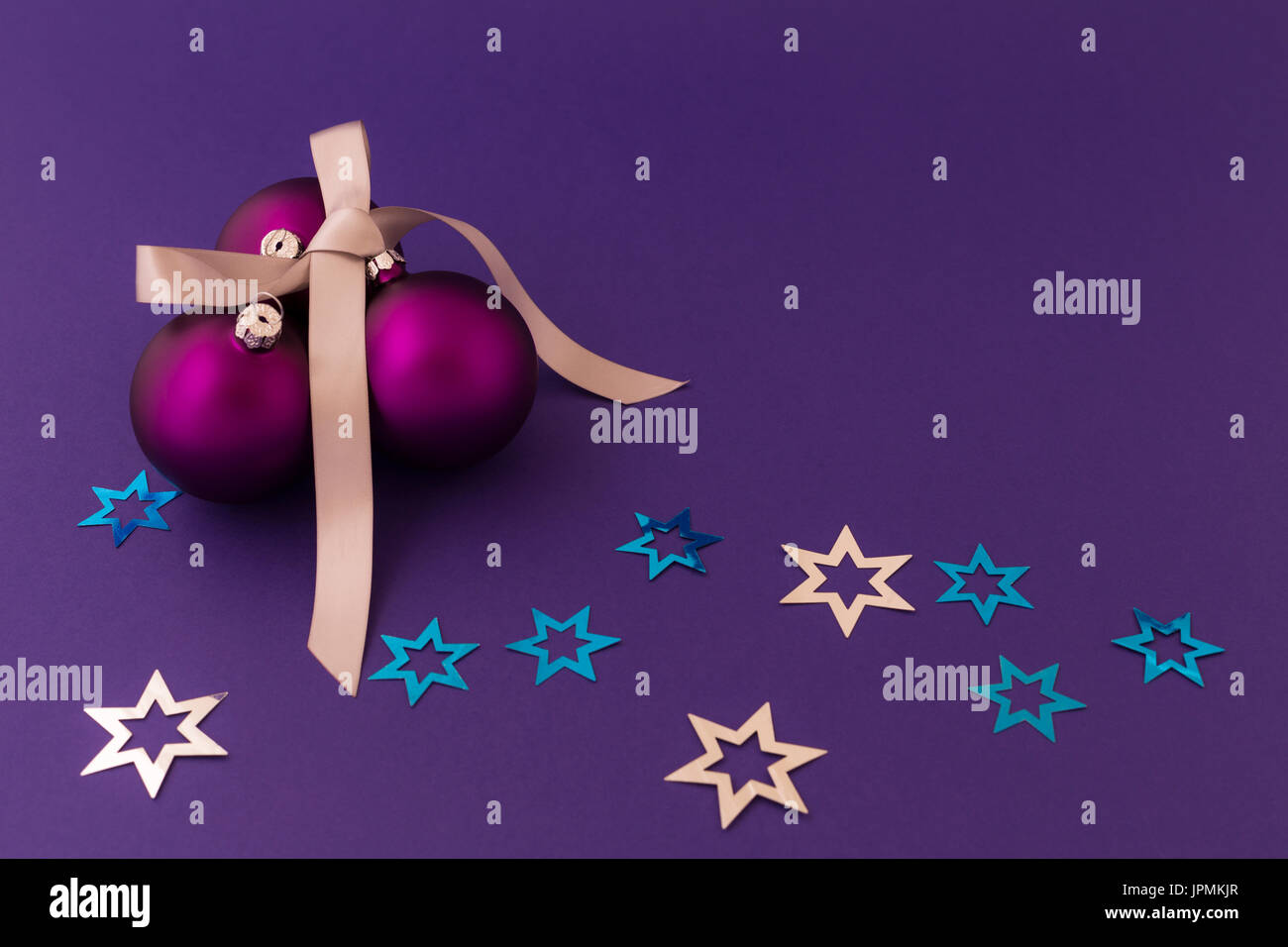 Bella viola le palle di Natale con effetto satinato, grigio dono ribbon e argento metallizzato e stelle blu su sfondo viola. Foto Stock