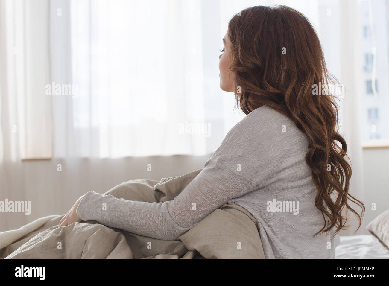 Donna seduta sul letto in mattina vista posteriore Foto Stock