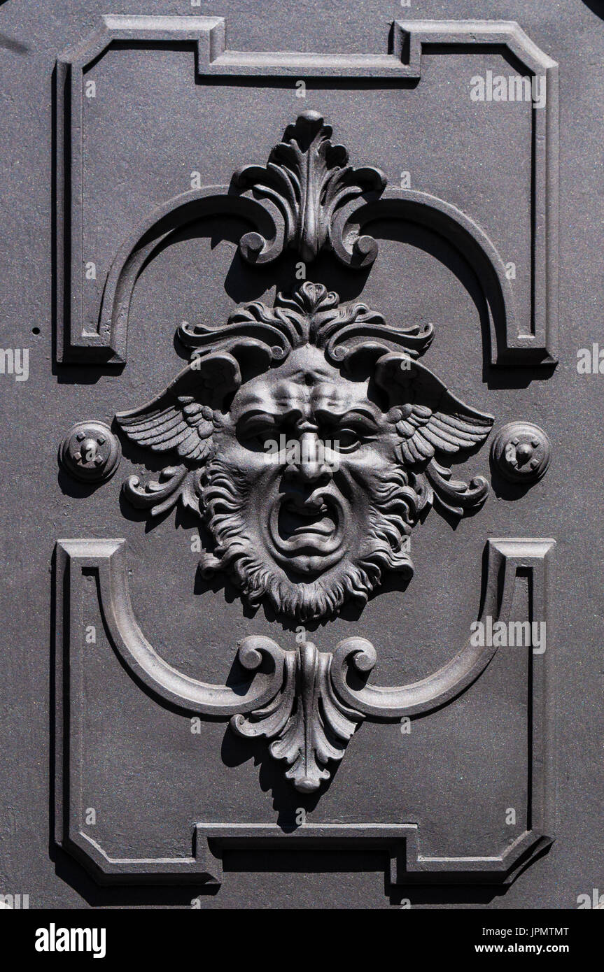 Milano, Italia: elementi in ferro battuto, una porta decorata con l'incisione di una maschera apotropaica Foto Stock