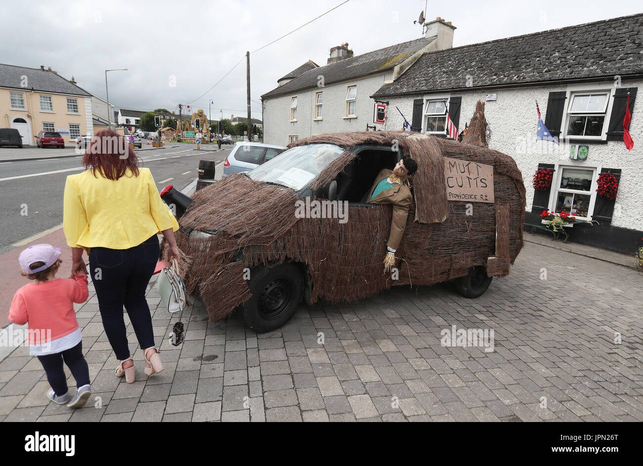 Le persone passano uno spaventapasseri intitolata 'Dumb e scemo' all'Durrow Spaventapasseri Festival che si svolge annualmente in Durrow, Co. Laois, Irlanda. Foto Stock