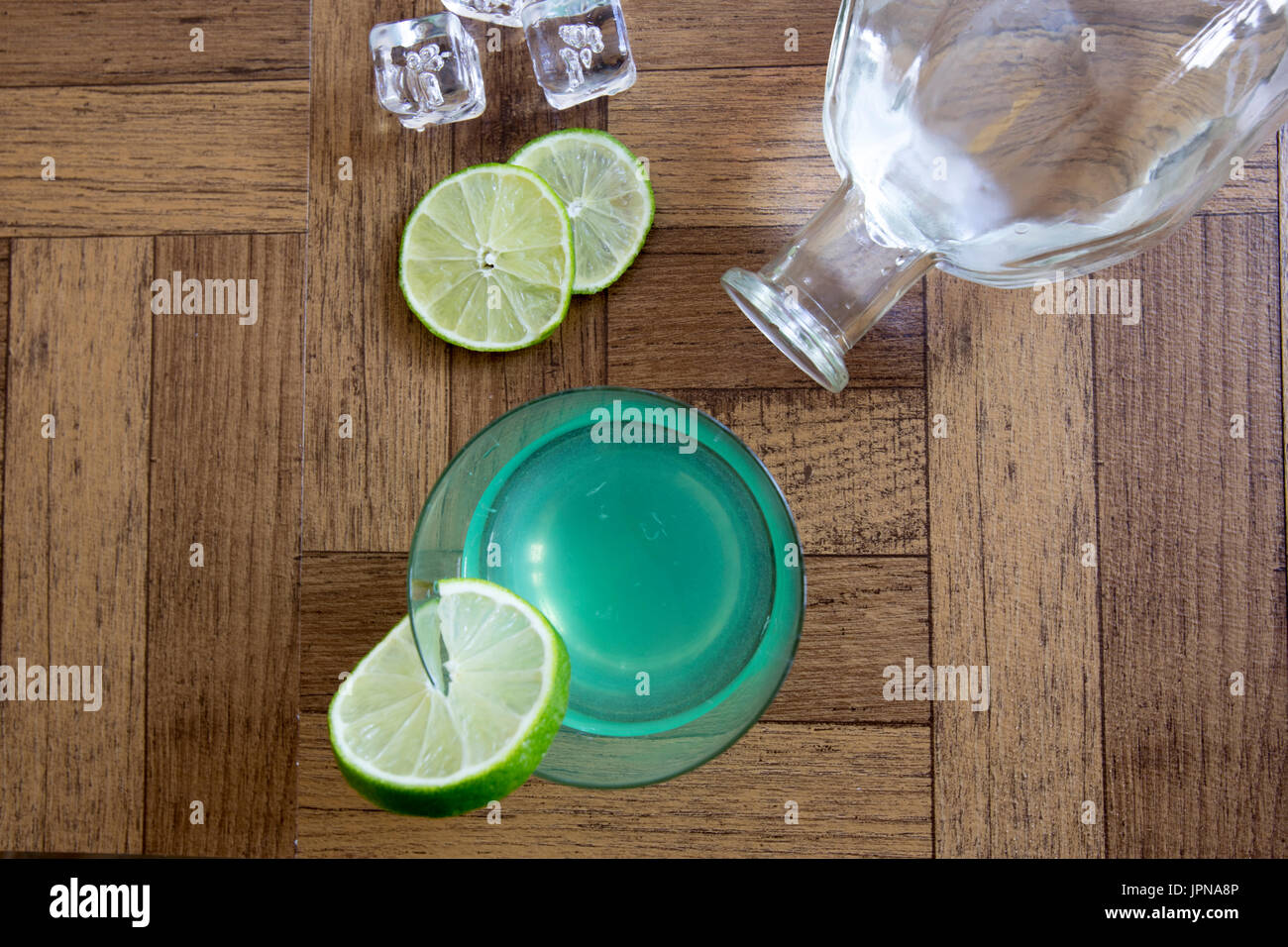 Vintage gin succhiello cocktail in alta sfera di vetro con fettine di lime, i cubetti di ghiaccio e una bottiglia di vetro su tavole di legno. Foto Stock
