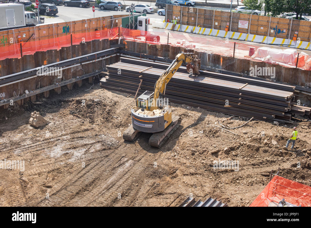 Un cingolato escavatore benna usata come una pinza rotante mover con tracce continue e gru di sollevamento su un sito in costruzione nella città di New York Foto Stock