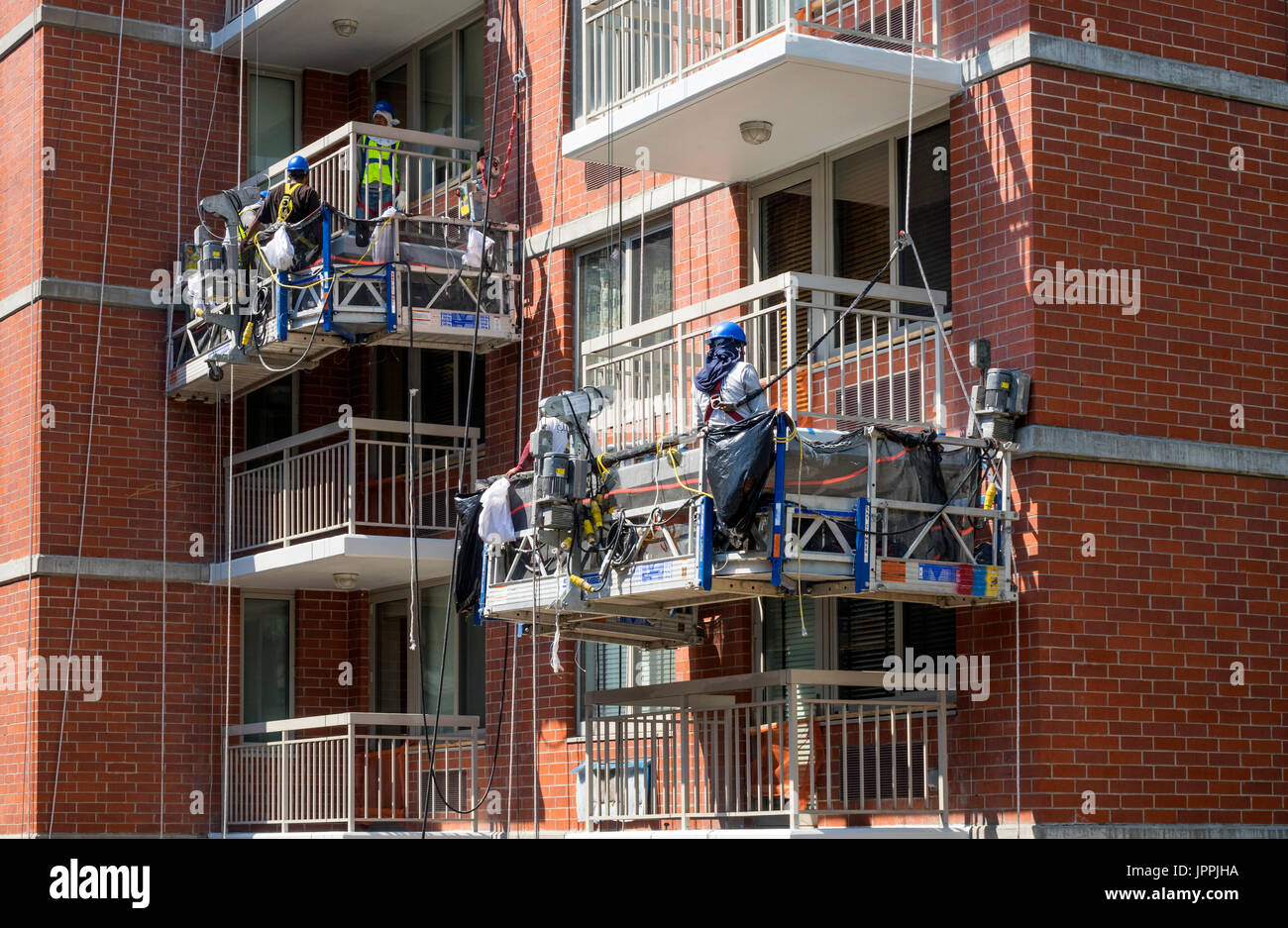 Lavoratori di manutenzione vestito n sicurezza pulizia ingranaggi terrazze di un edificio di appartamenti nella città di New York Foto Stock