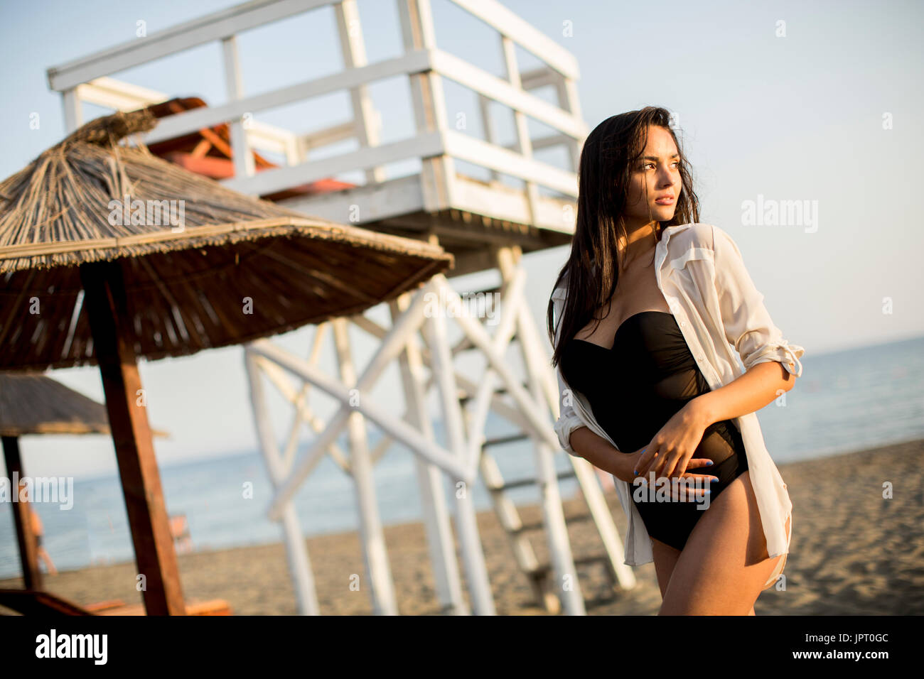 Vista in giovane donna in posa sulla spiaggia da bagnino torre di osservazione Foto Stock