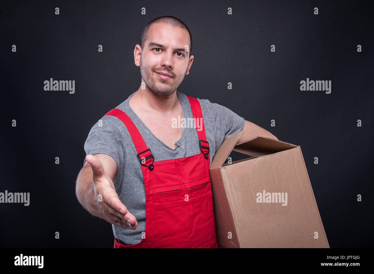Mover guy scatola di contenimento che offre il tremolio delle mani come chiusura trattativa o lavoro concetto su sfondo nero Foto Stock