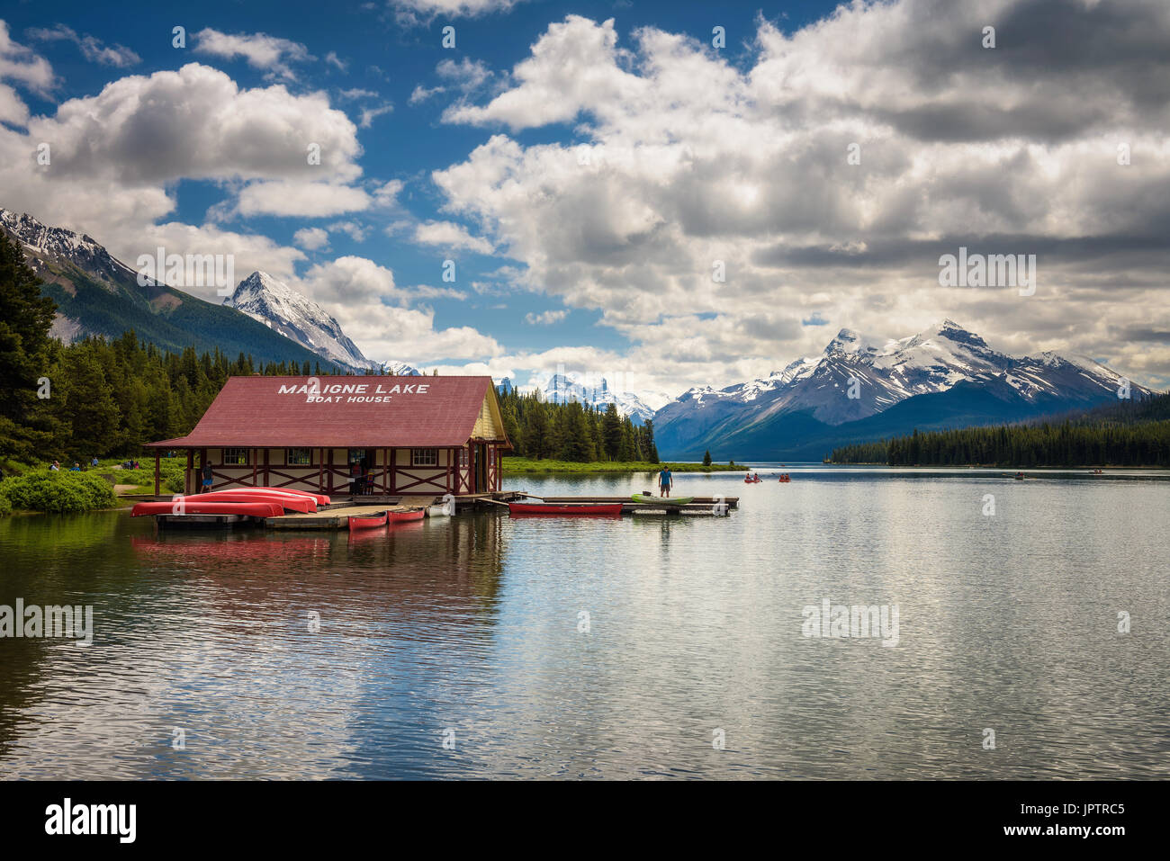 Casa delle barche e canoe su un molo al Lago Maligne nel Parco Nazionale di Jasper, Canada, con cime innevate della Canadian Rocky Mountains in backgroun Foto Stock