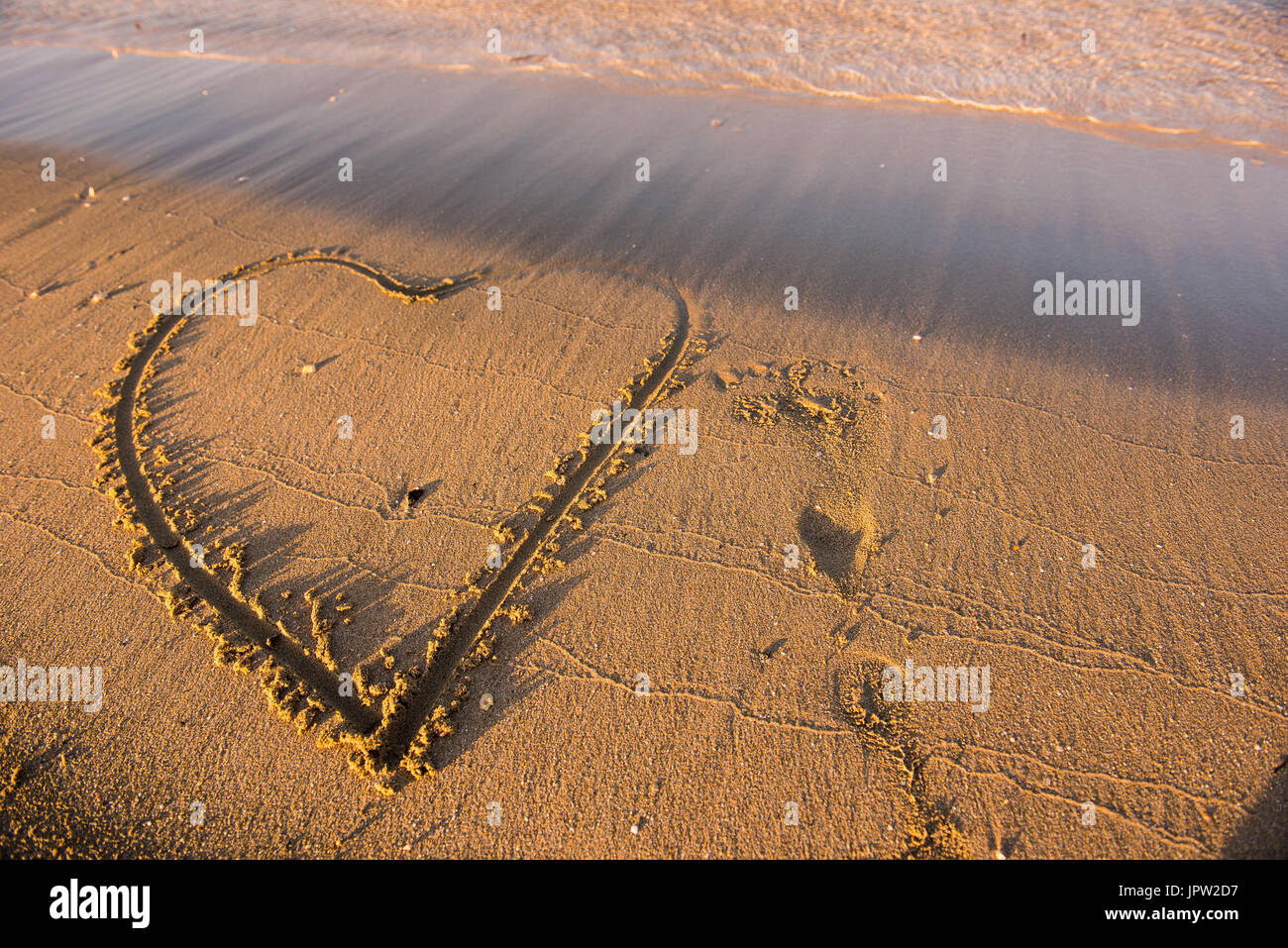 Cuore disegnato sulla sabbia. Le onde si avvicinano. Estate spiaggia Concetto di vacanza Foto Stock