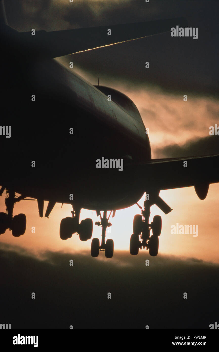 Boeing 747 sul finale-approccio al tramonto con il carro verso il basso e scuro-nuvole Foto Stock