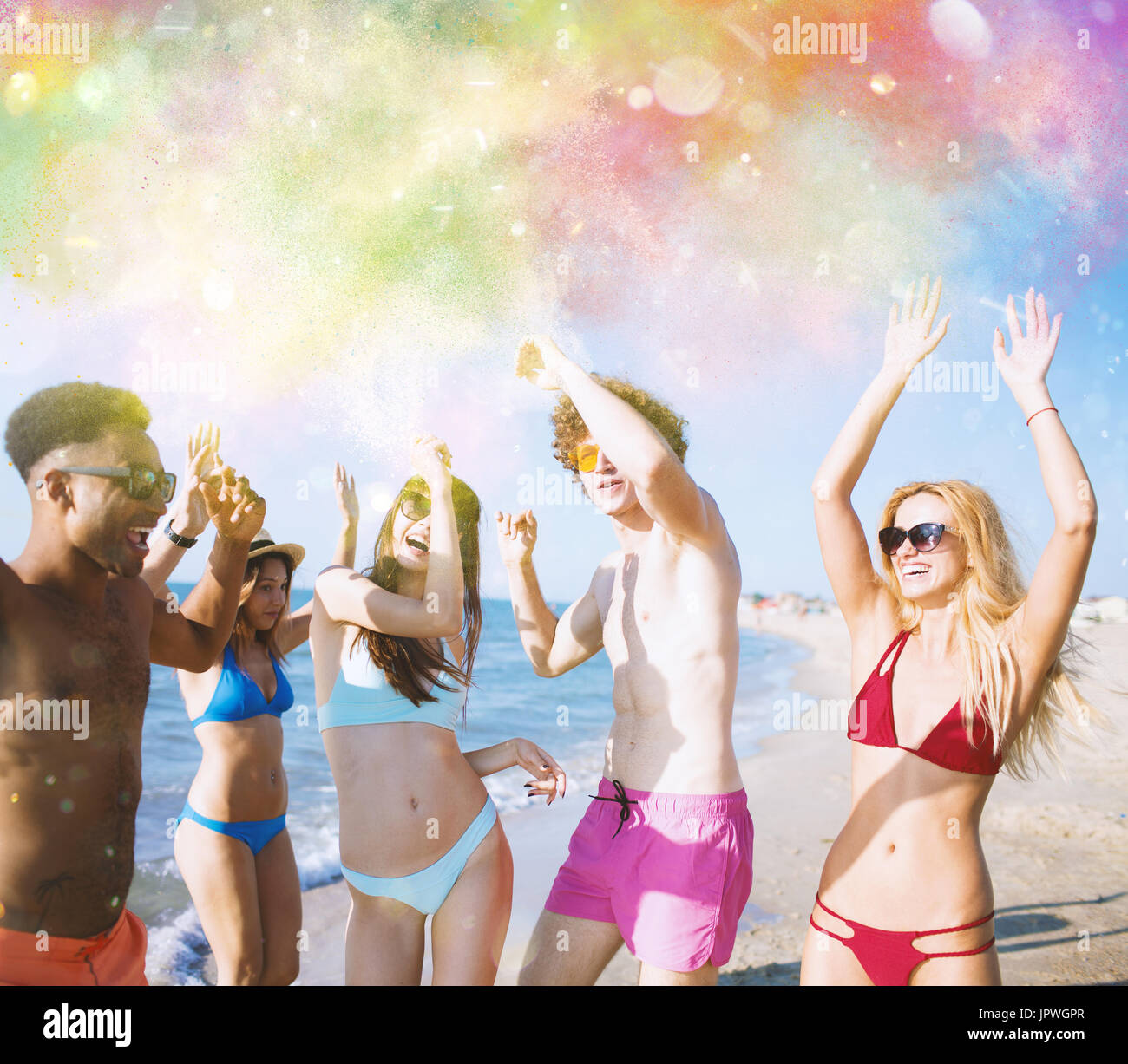 Gruppo di amici ballare sotto un colore splash Foto Stock