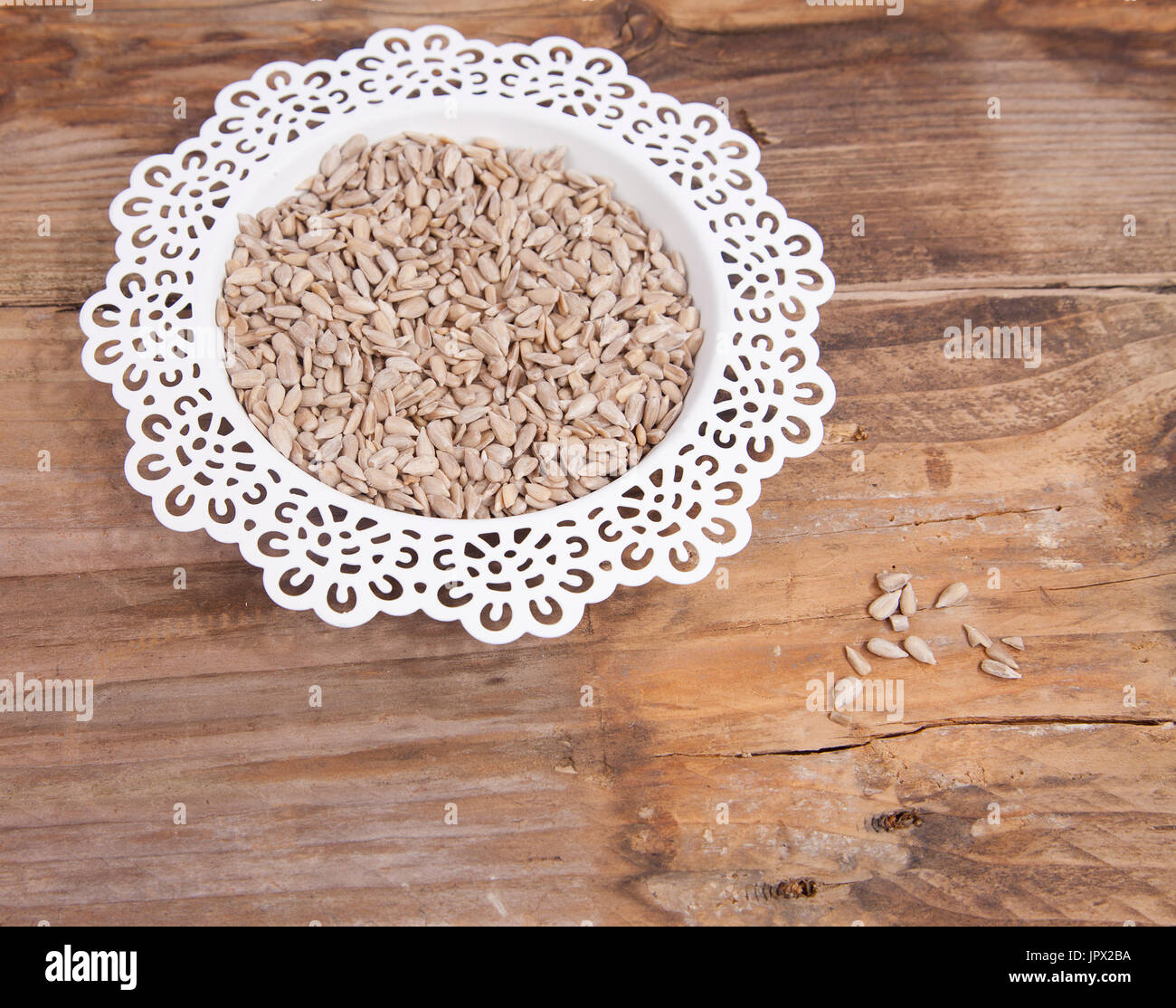 Semi di girasole in vaschetta bianca su sfondo di legno Foto Stock